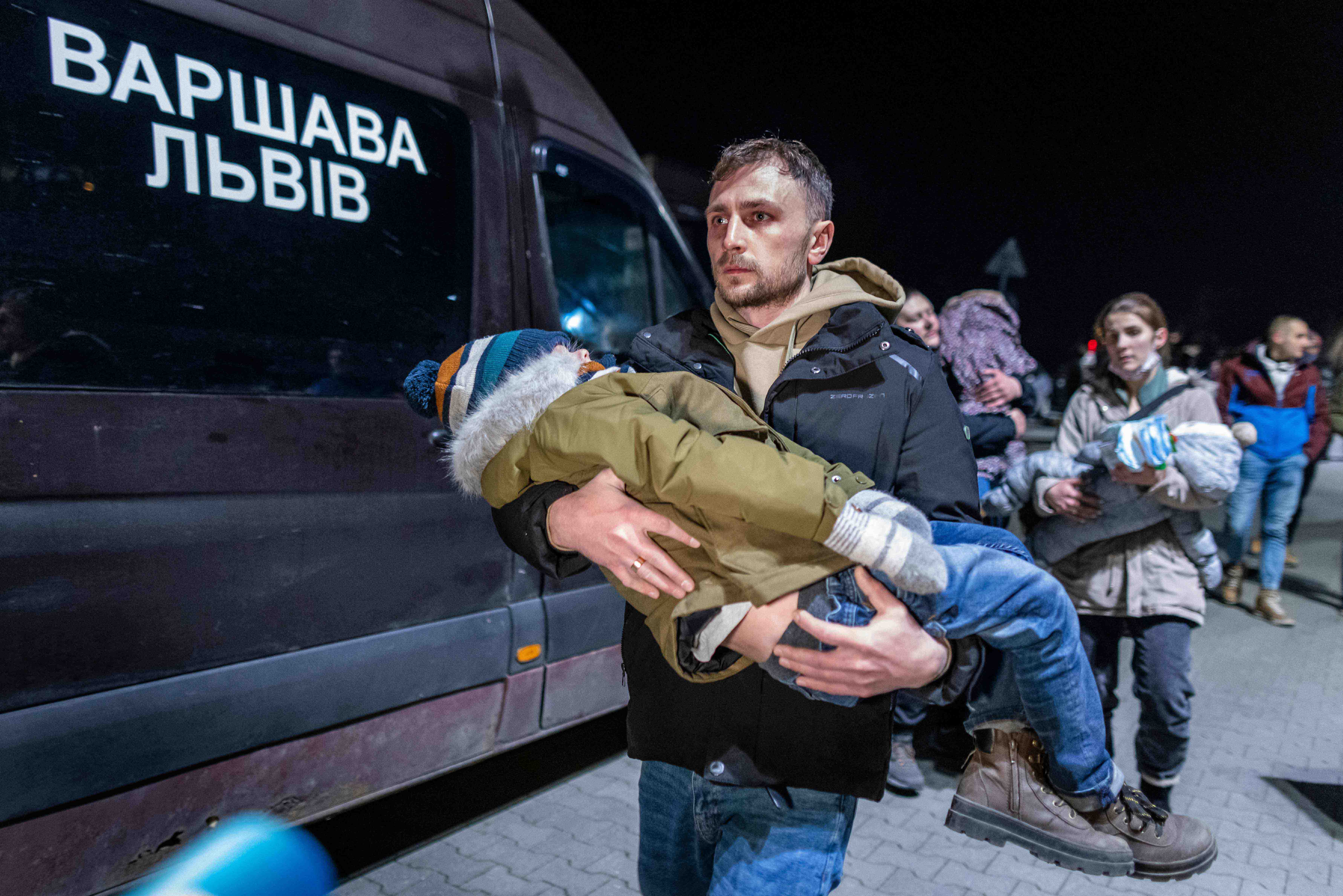 A volunteer carries a Ukranian child as civilians fleeing the conflict in Ukraine, arrive on buses in Przemsyl, eastern Poland, from the Medyka pedestrian border crossing.