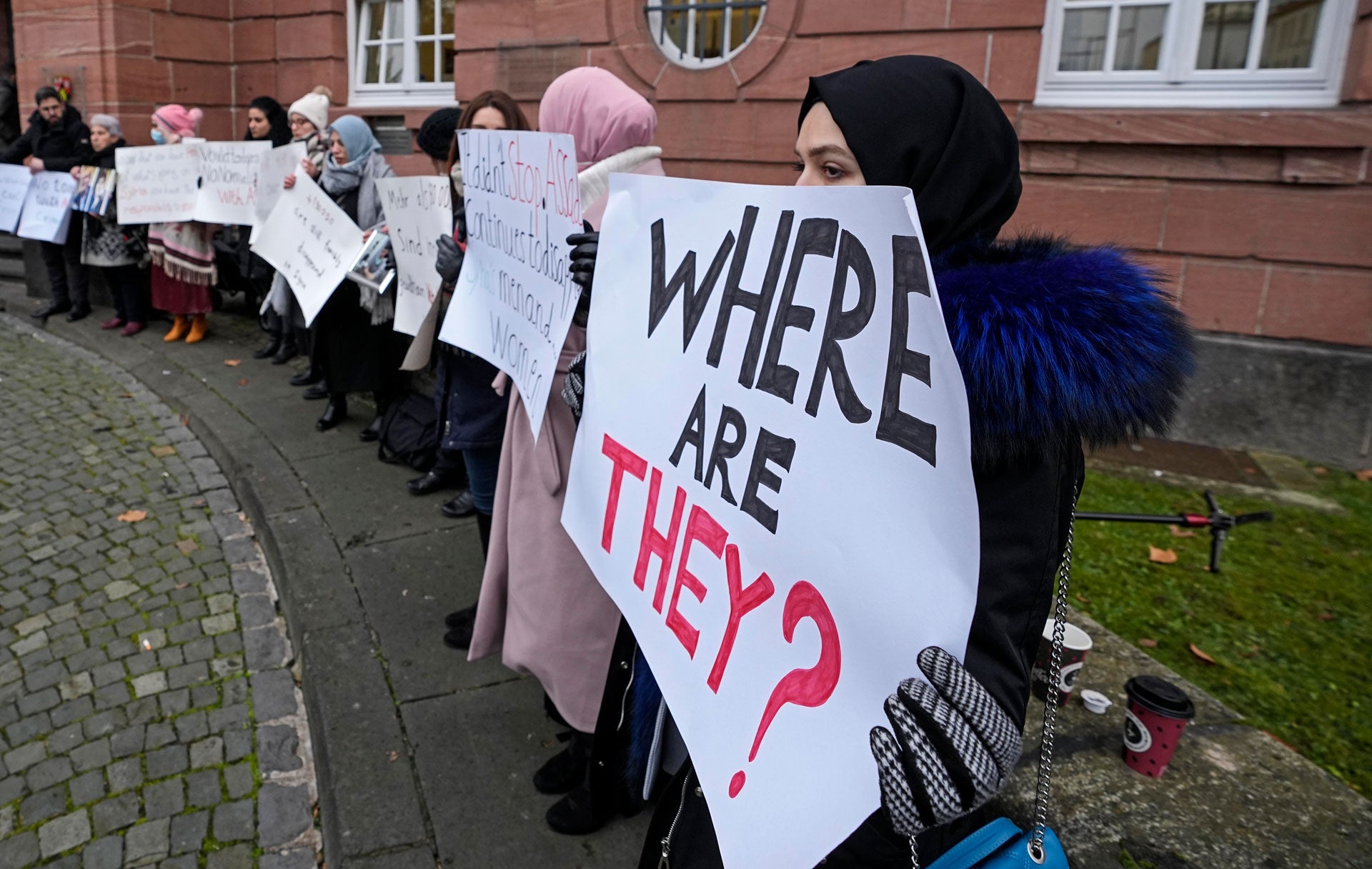 Women hold banners with phrases on them. One reads, "Where are they?"