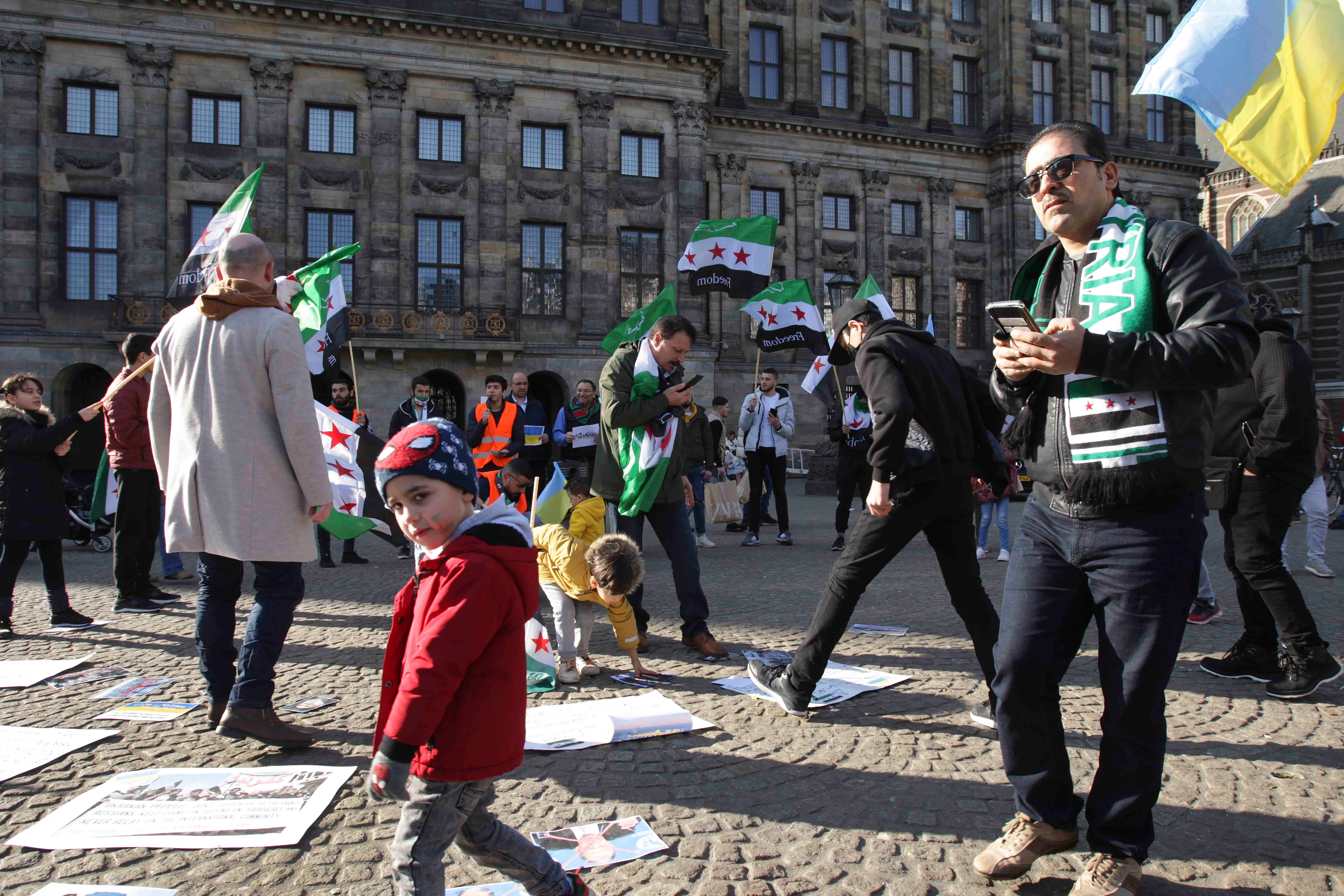 سوريون يشاركون في مظاهرة "سوريا بدها حرية" احتجاجا على هجمات القوات المسلحة السورية وحلفائها على المدنيين، بالإضافة إلى الاجتياح الروسي الشامل لأوكرانيا في ساحة دام، 26 فبراير/شباط 2022 في أمستردام، هولندا. 