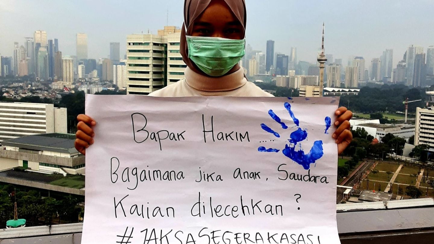 A Universitas Riau student, who accompanied a sexual harassment victim in Pekanbaru, holds a protest sign after the defendant was acquitted. It reads, “Mr. Judge, how would you react to your daughters or sisters being molested?”