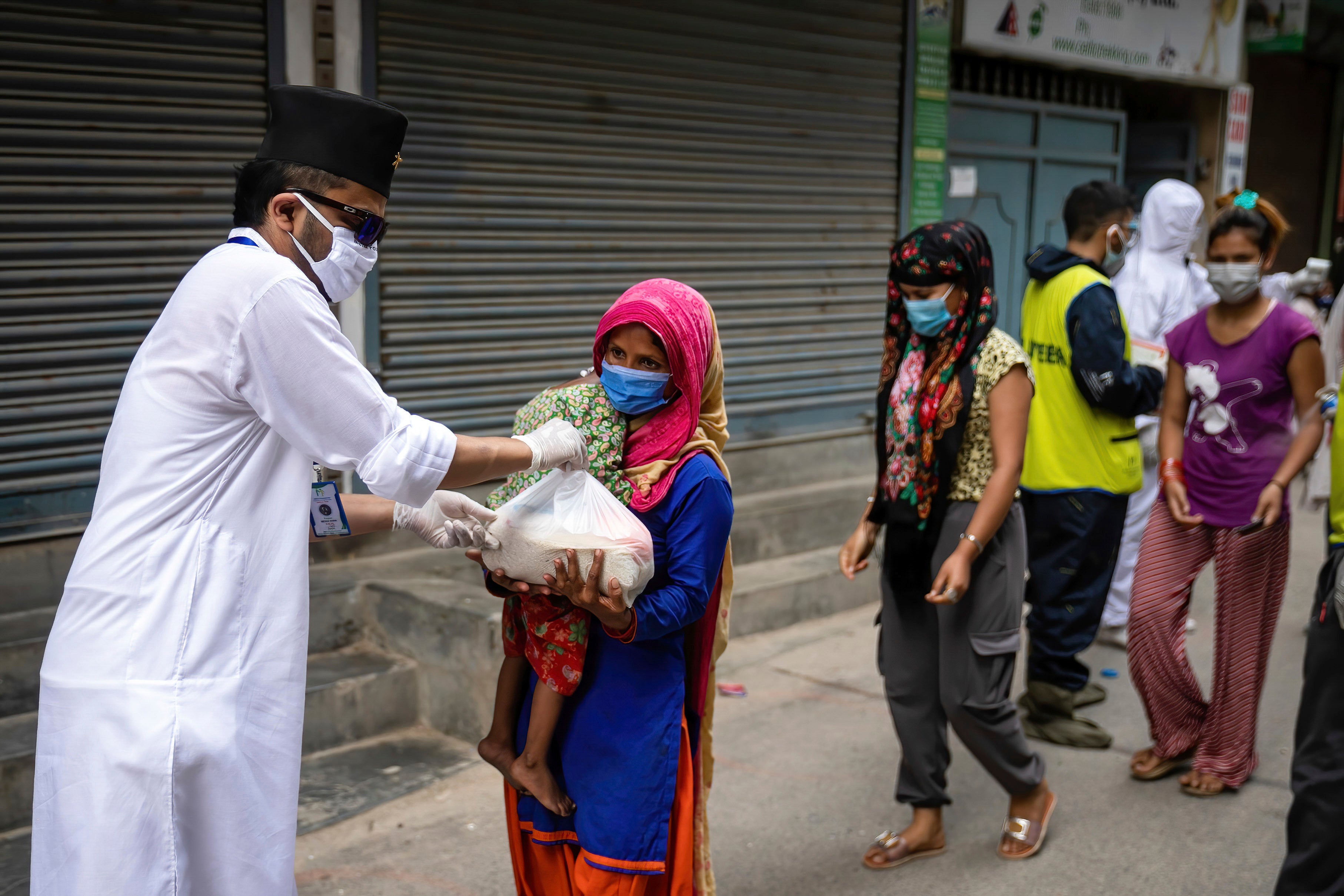 A woman and her child receive relief goods distributed by a community service center in Kathmandu, Nepal on June 4, 2021. 