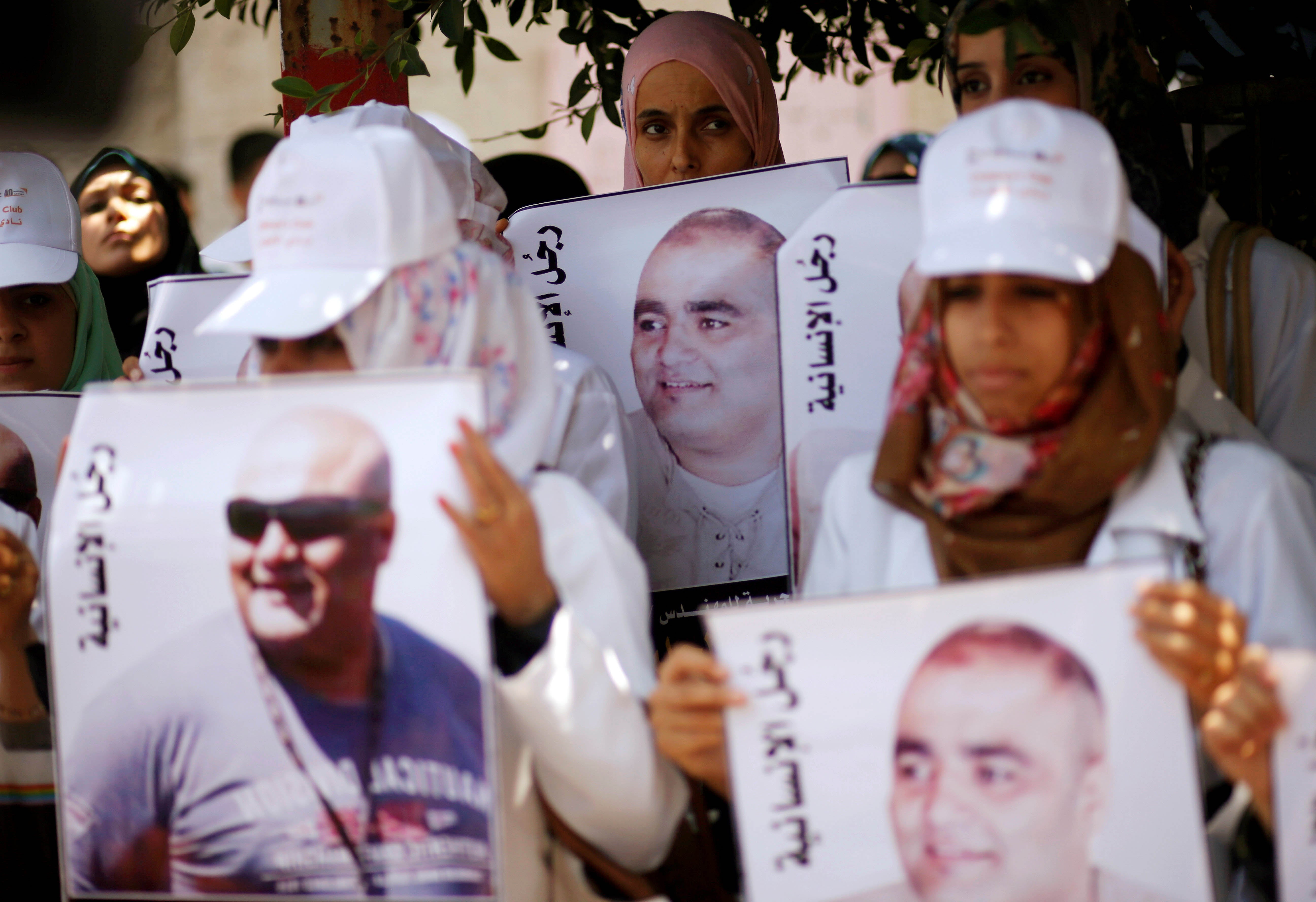 متظاهرون فلسطينيون يحملون صور محمد الحلبي، وهو موظف إغاثة في غزة تحتجزه إسرائيل منذ يونيو/حزيران 2016 بدون إدانته بجريمة، خلال مظاهرة تضامن مع الحلبي، مدينة غزة، 7 أغسطس/آب 2016.  