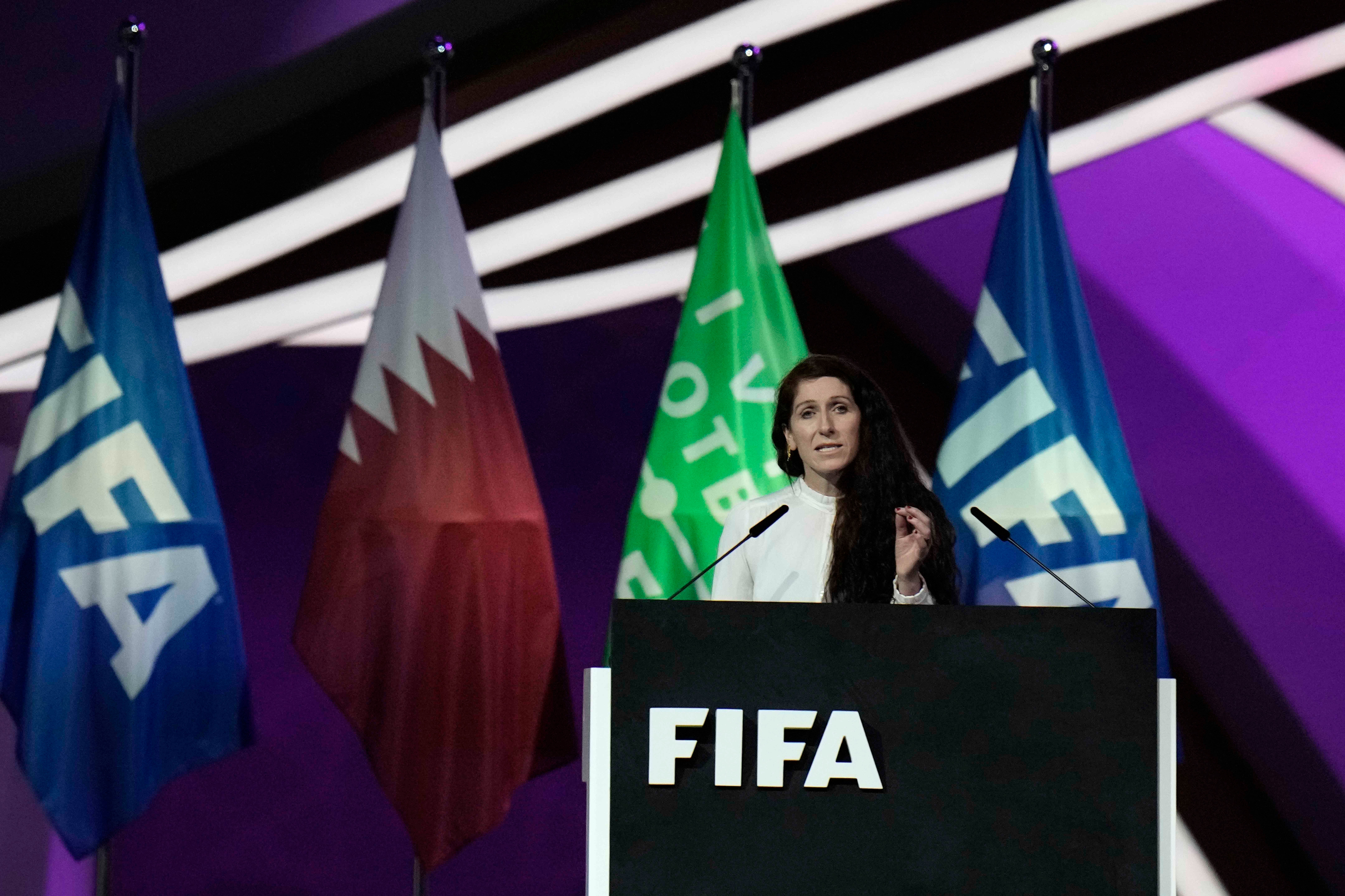 A woman speaks at a podium labeled "FIFA"