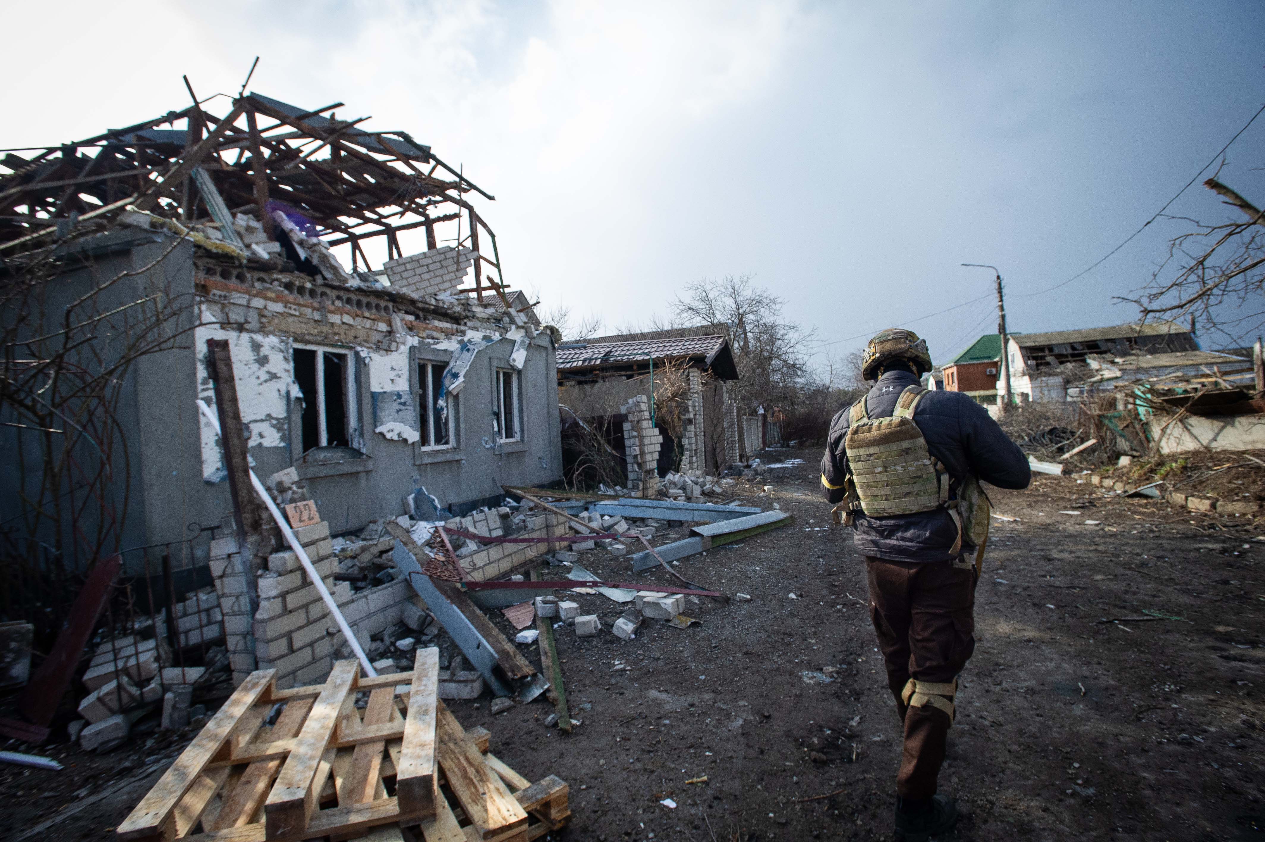 Un membre des forces armées ukrainiennes marchait devant les décombres  d'une maison endommagée par des roquettes tirées par les forces russes dans la périphérie sud de Mykolaïv, en Ukraine, le 9 mars 2022.