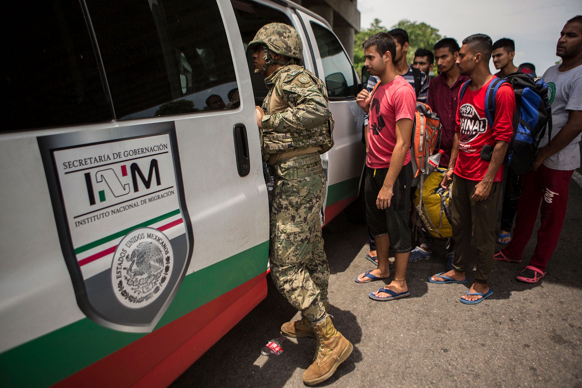 A Mexican Marine orders a group of migrants from Bangladesh, India and Pakistan off a bus at an immigration checkpoint