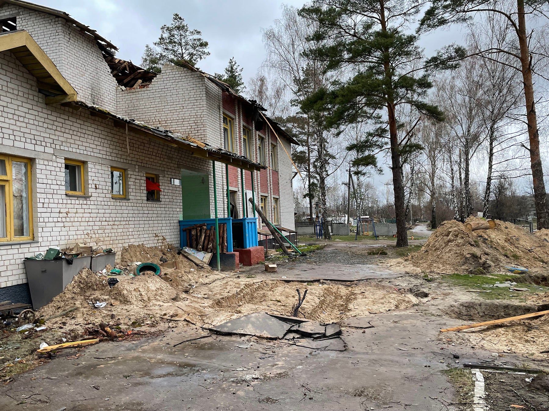 Gruben im Schulhof von Yahidne, die offensichtlich von den russischen Truppen genutzt wurden, Yahidne, 17. April 2022.