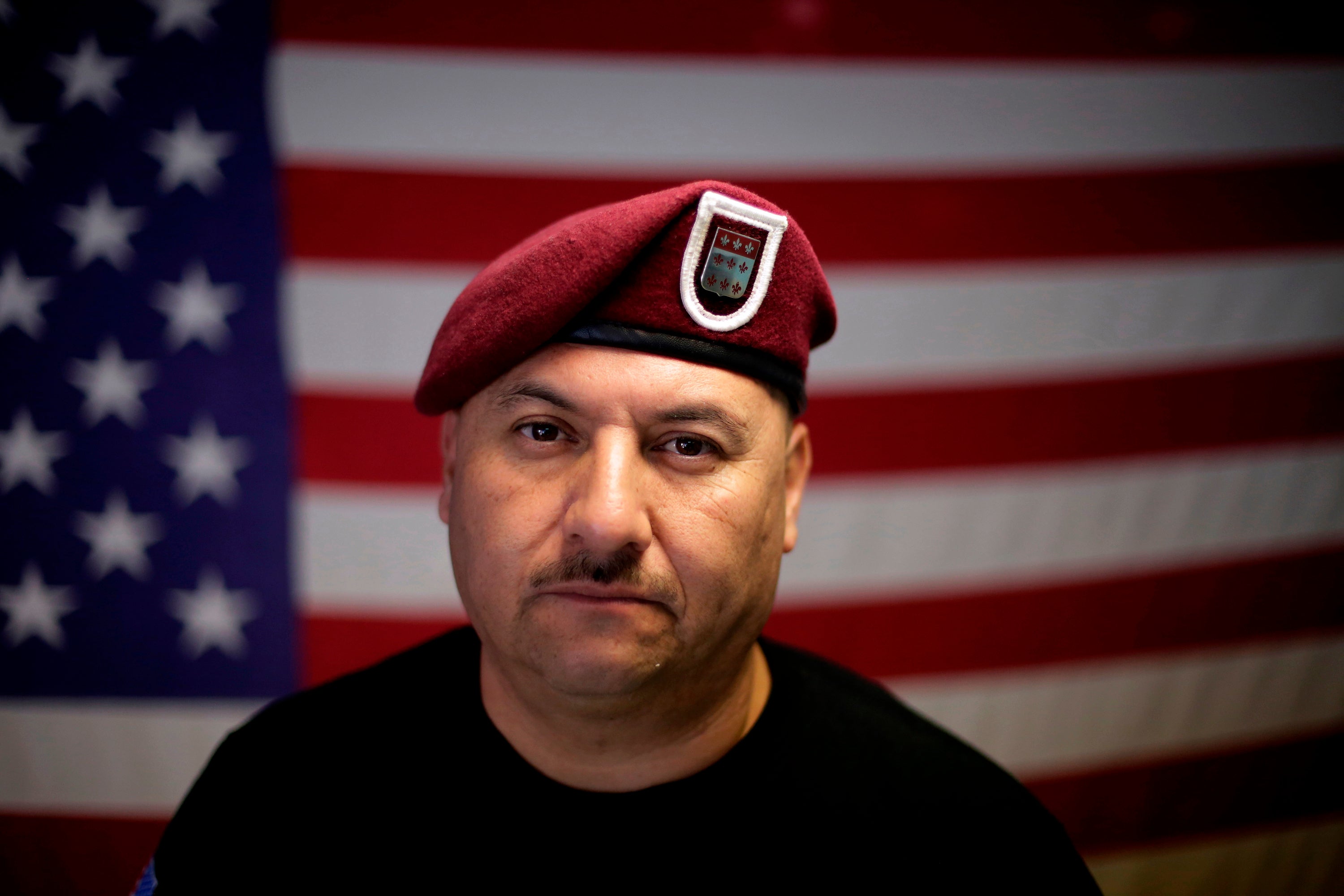 A man poses for a photo in front of an American flag
