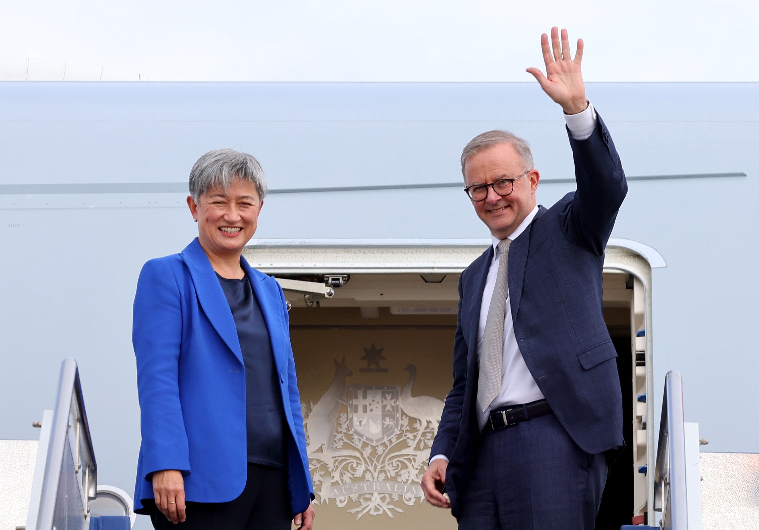 Australian Prime Minister Anthony Albanese waves alongside newly appointed Foreign Minister Penny Wong at the door of their plane
