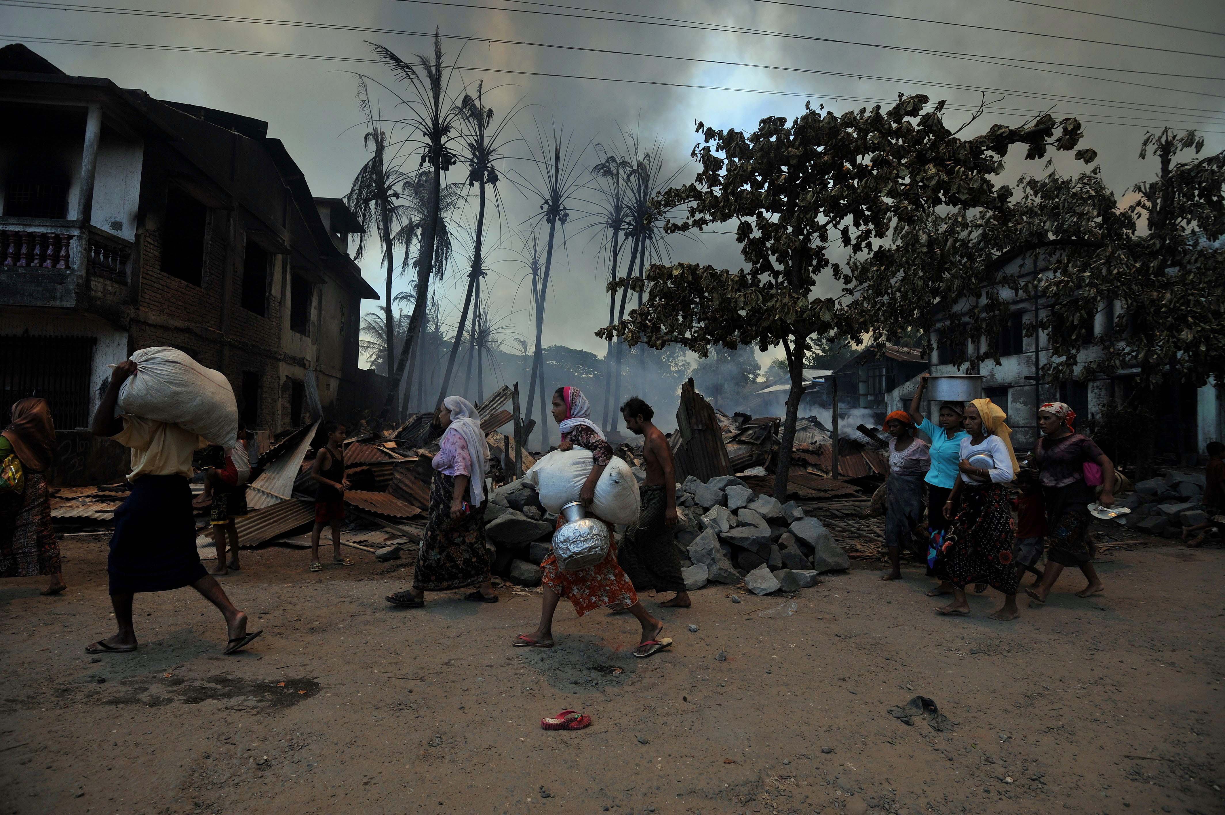 Des Rohingyas fuient leurs maisons avec leurs affaires au milieu des violences à Sittwe