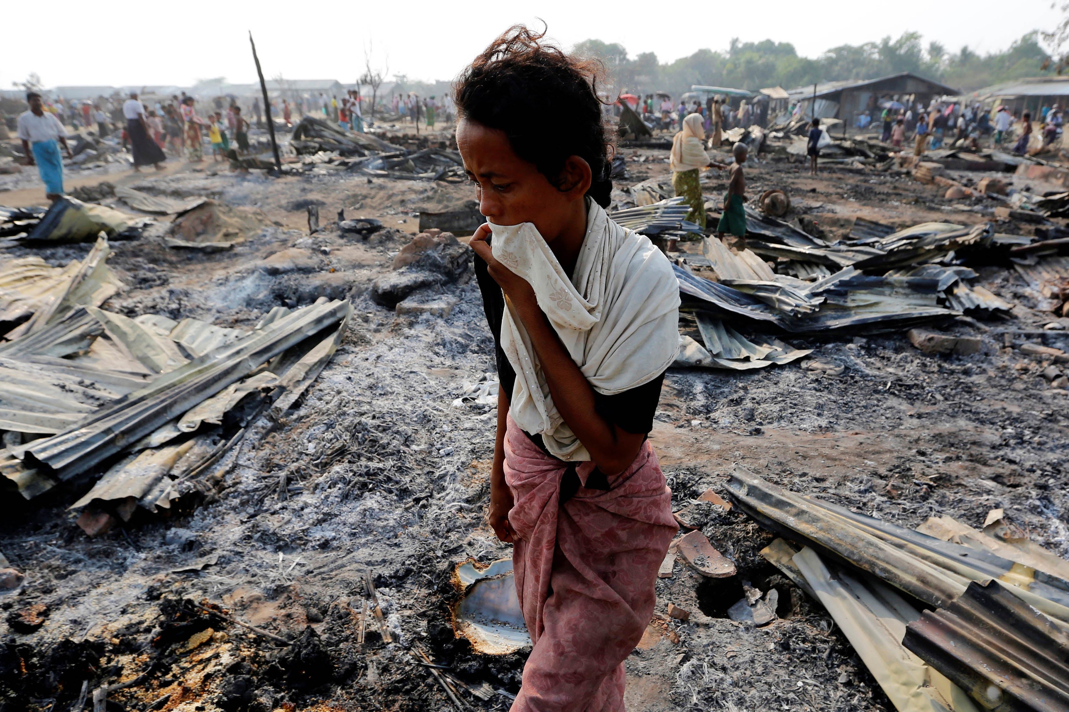 Une femme rohingya marche parmi des débris après qu'un incendie ait détruit des abris dans son camp à Sittwe