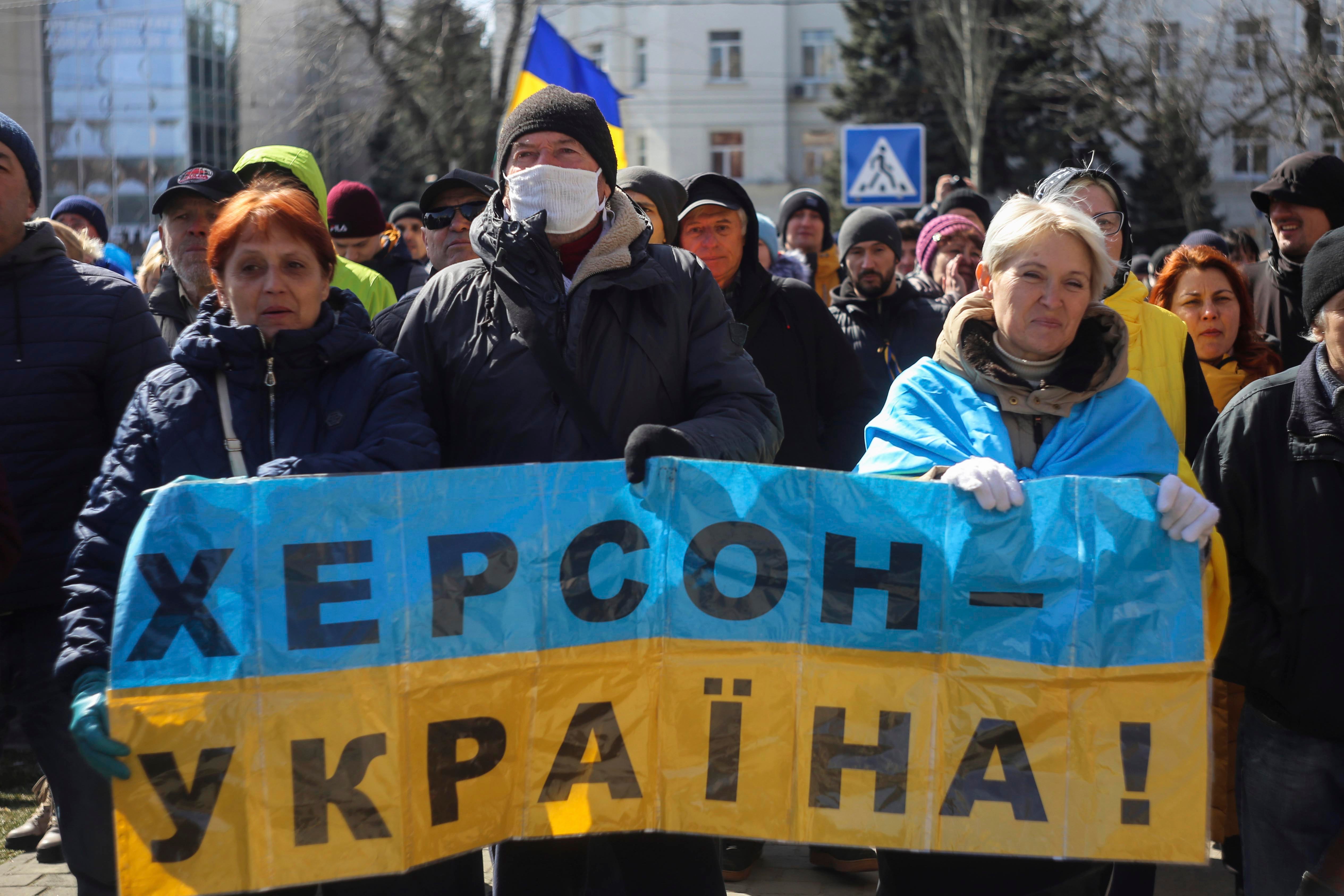 Люди тримають український прапор із написом «Херсон – Україна» під час мітингу протесту проти російської окупації. Херсон, Україна, неділя, 20 березня 2022 року. © 2022 Олександр Чорний/AP