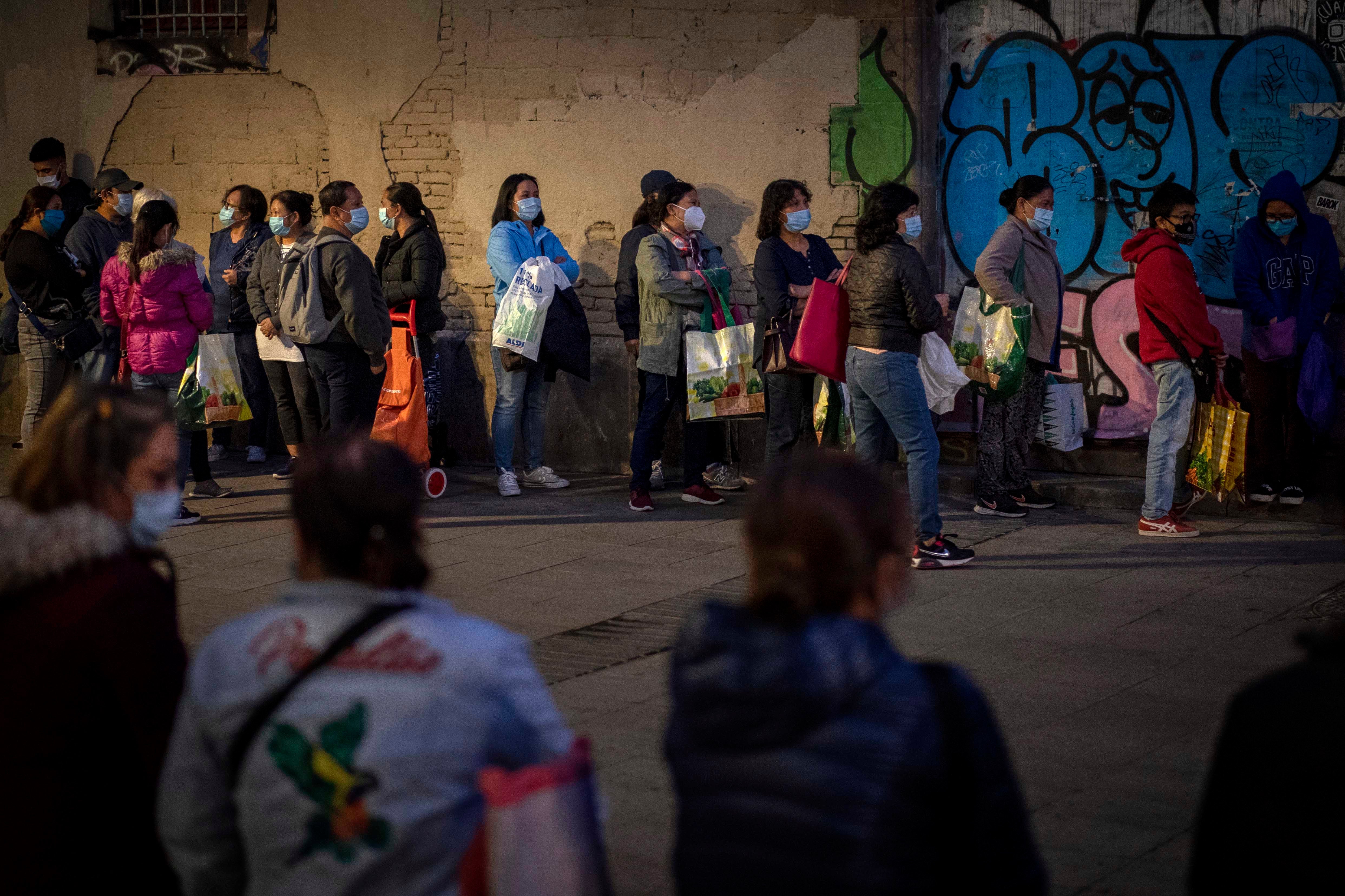 Decenas de personas hacen cola para recibir alimentos donados en Barcelona, España, 10 de noviembre de 2020.