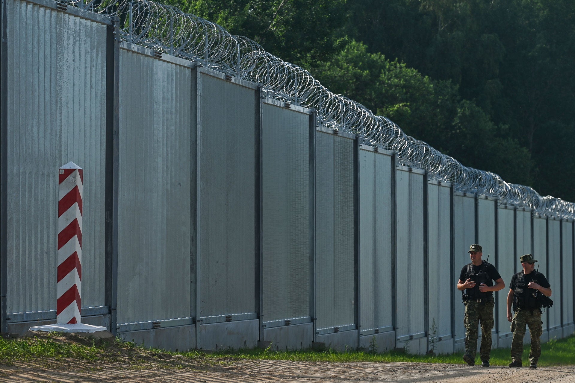 Polish border guards patrol along a fence