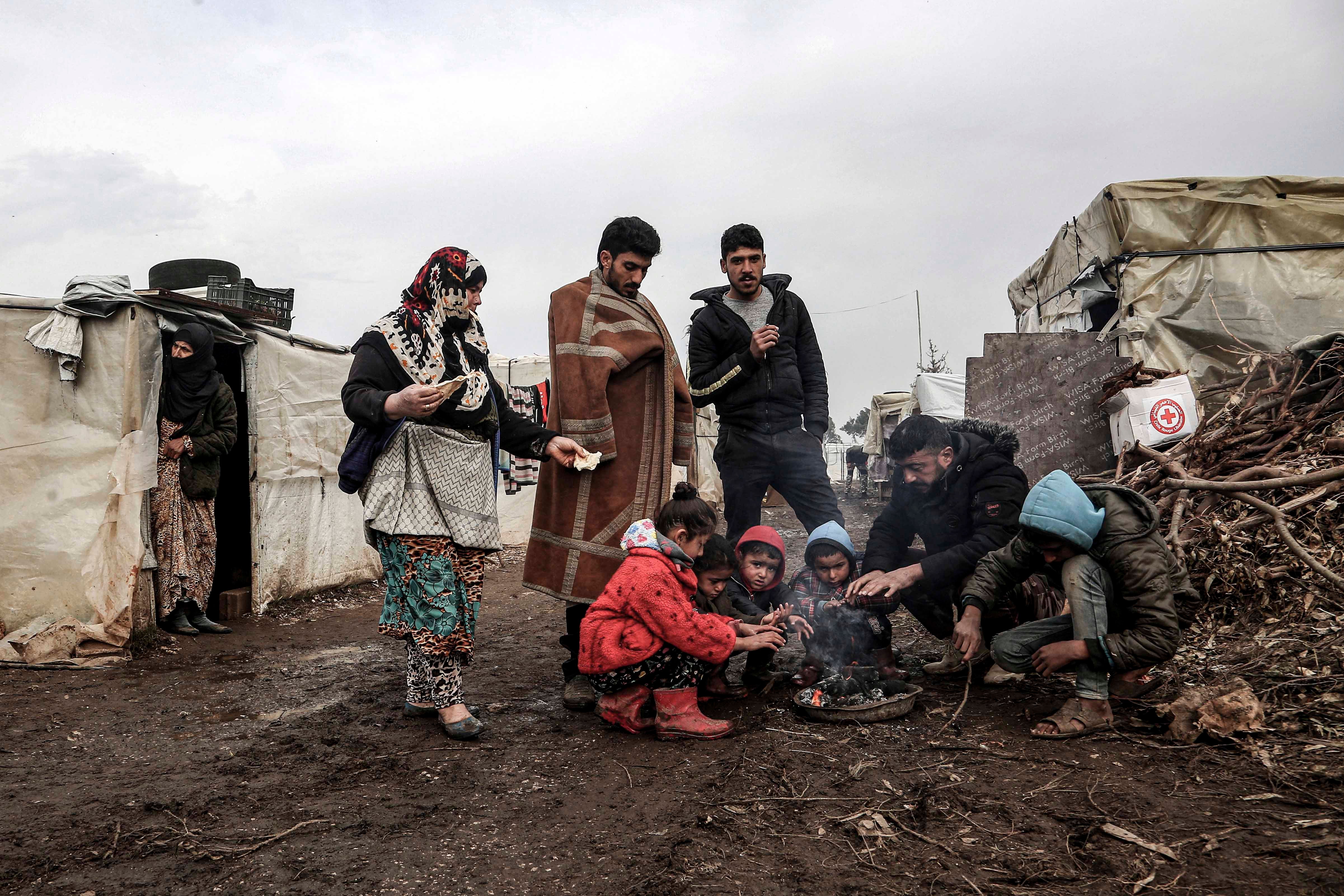 مجموعة من السوريين يتجمعون حول موقدة صغيرة في مخيم في قرية السماقية في شمال لبنان على بعد بضع مئات أمتار من الحدود اللبنانية-السورية، 31 يناير/كانون الثاني 2022. 