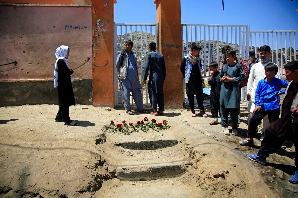 Des personnes se recueillaient, le 9 mai 2021, devant des fleurs posées en hommage aux jeunes victimes d'une attaque meurtrière perpétrée la veille contre une école dans un quartier habité principalement par des membres de la minorité Hazara à Kaboul, en Afghanistan.