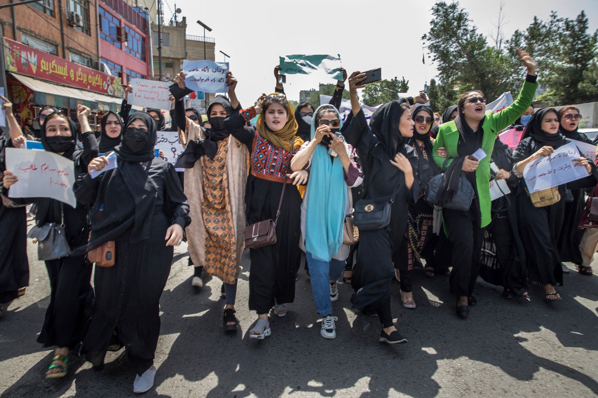 Women march and chant, holding signs during a protest