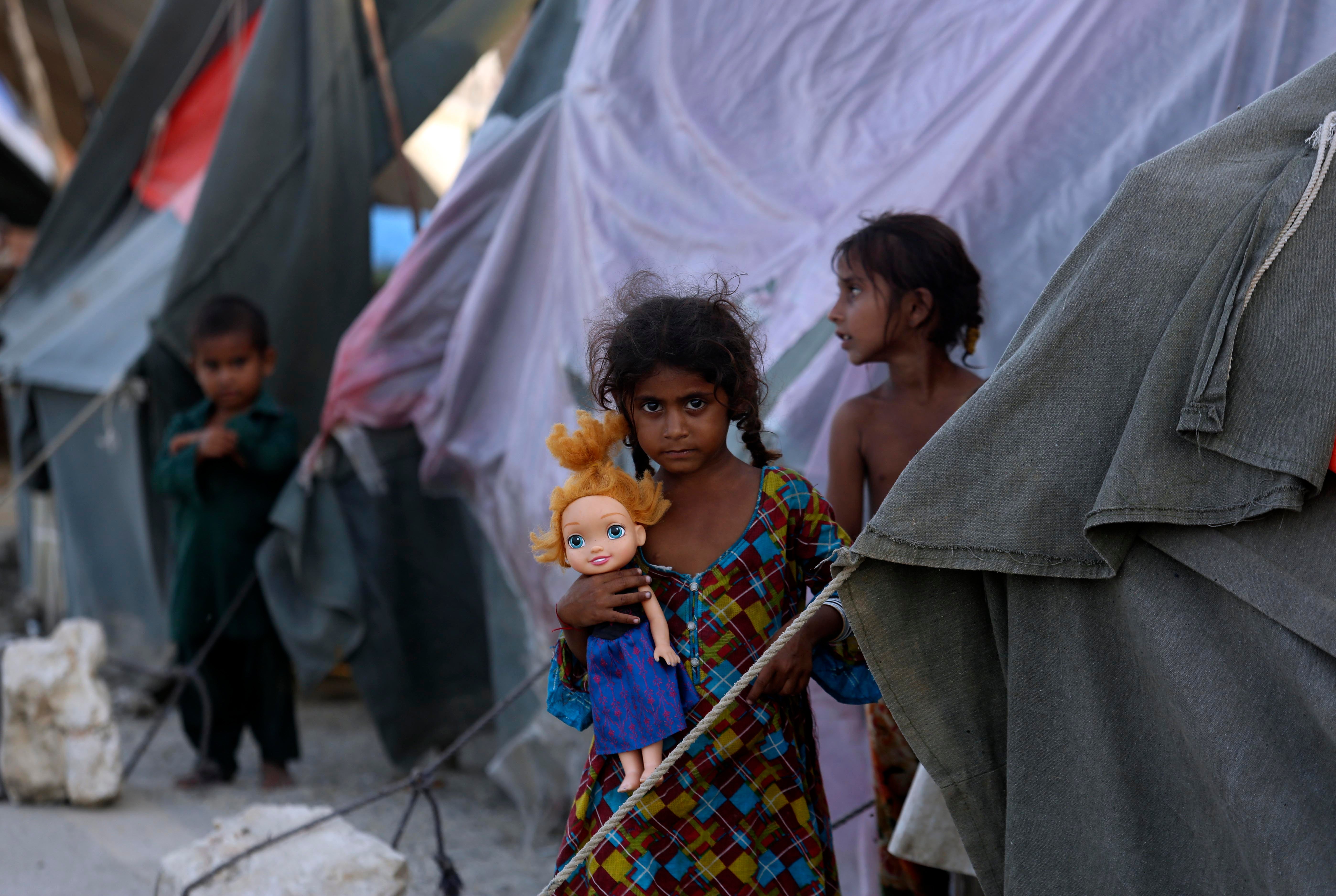 Children stand outside tents