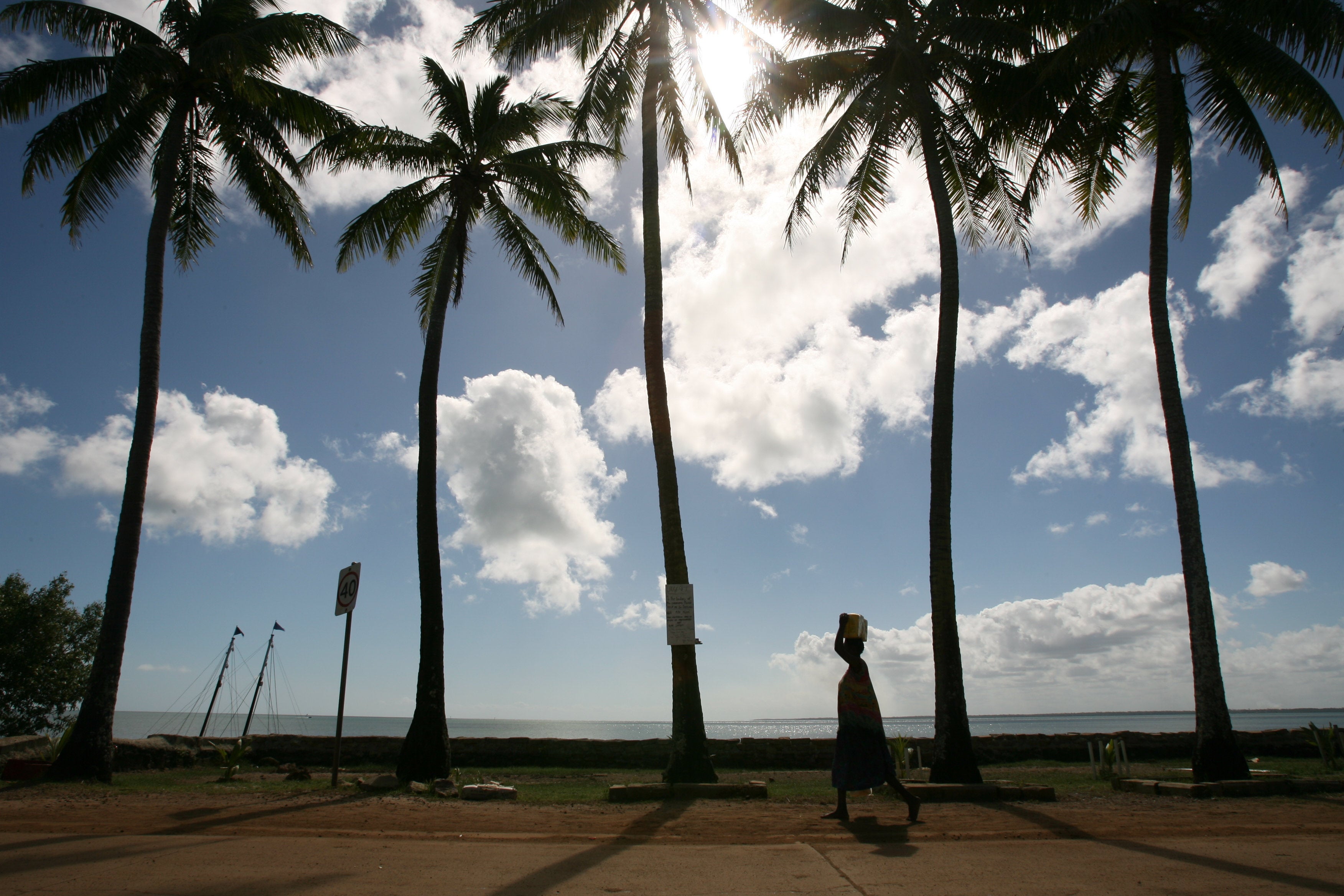 A woman walks past palm trees on Saibai Island in the Torres Strait