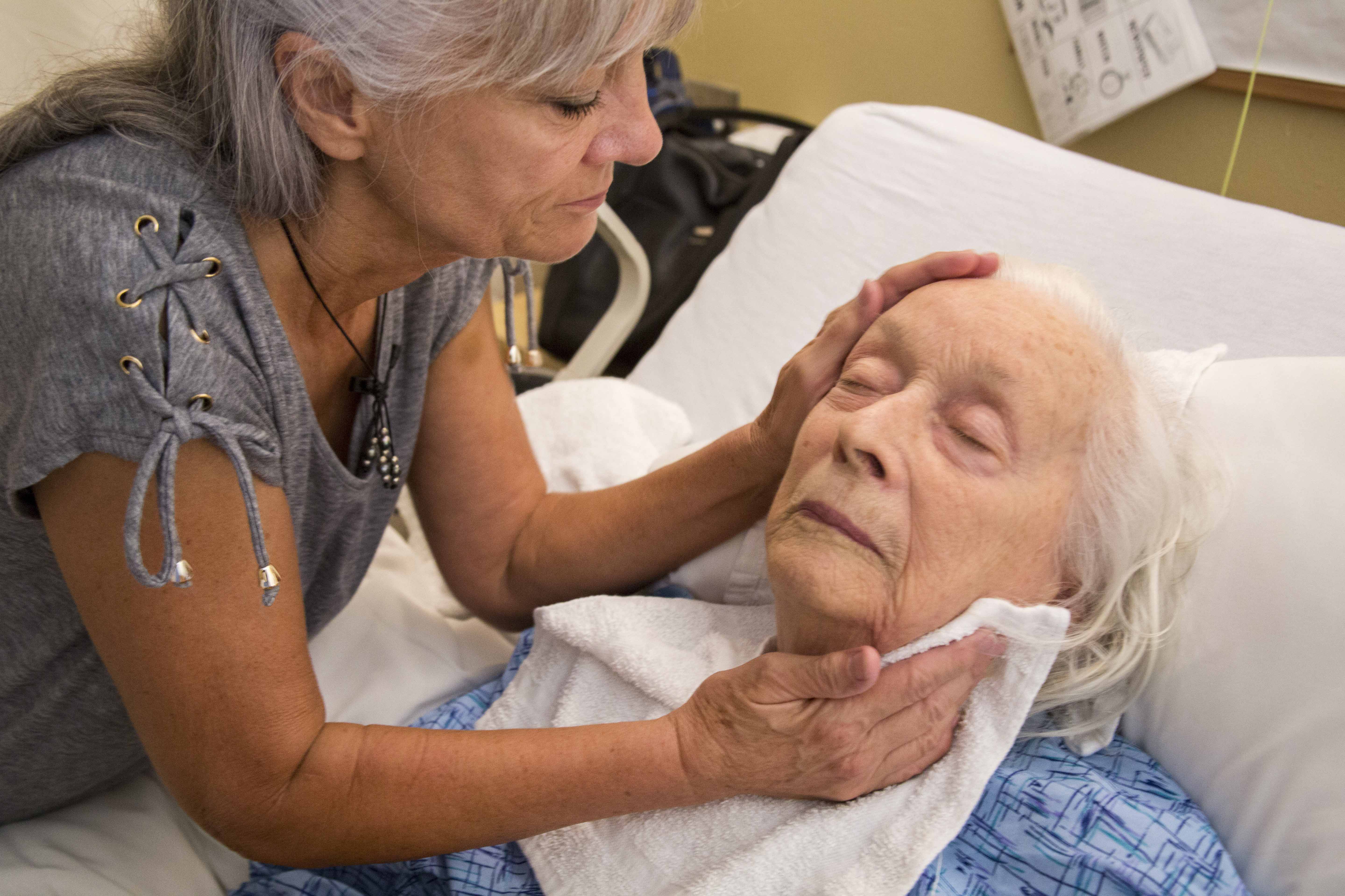 A woman tends to an older women lying in a bed