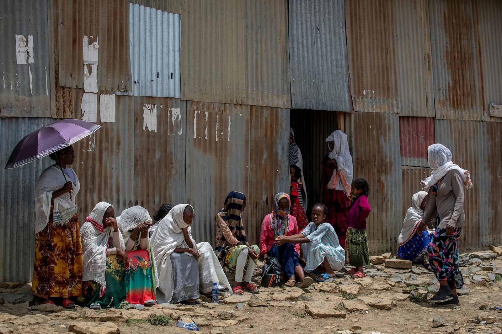 Displaced Tigrayans sit alongside metal shacks in Mekele, Ethiopia.