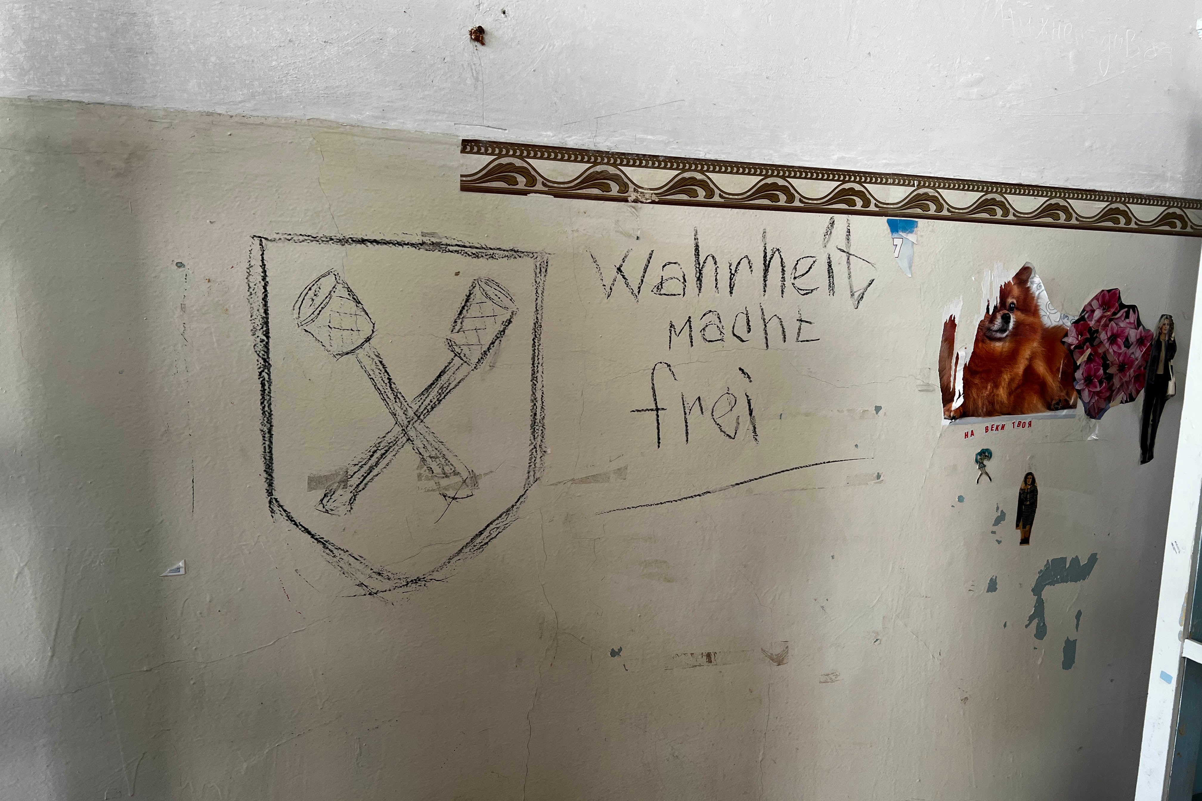 The German words “Truth Sets You Free” written on the wall in one of the City Railway Polyclinic rooms, and an emblem that might depict crossed stick grenades, which was the symbol of a German SS brigade from World War II, the Dirlewanger Brigade, in Izium, Ukraine, September 22, 2022