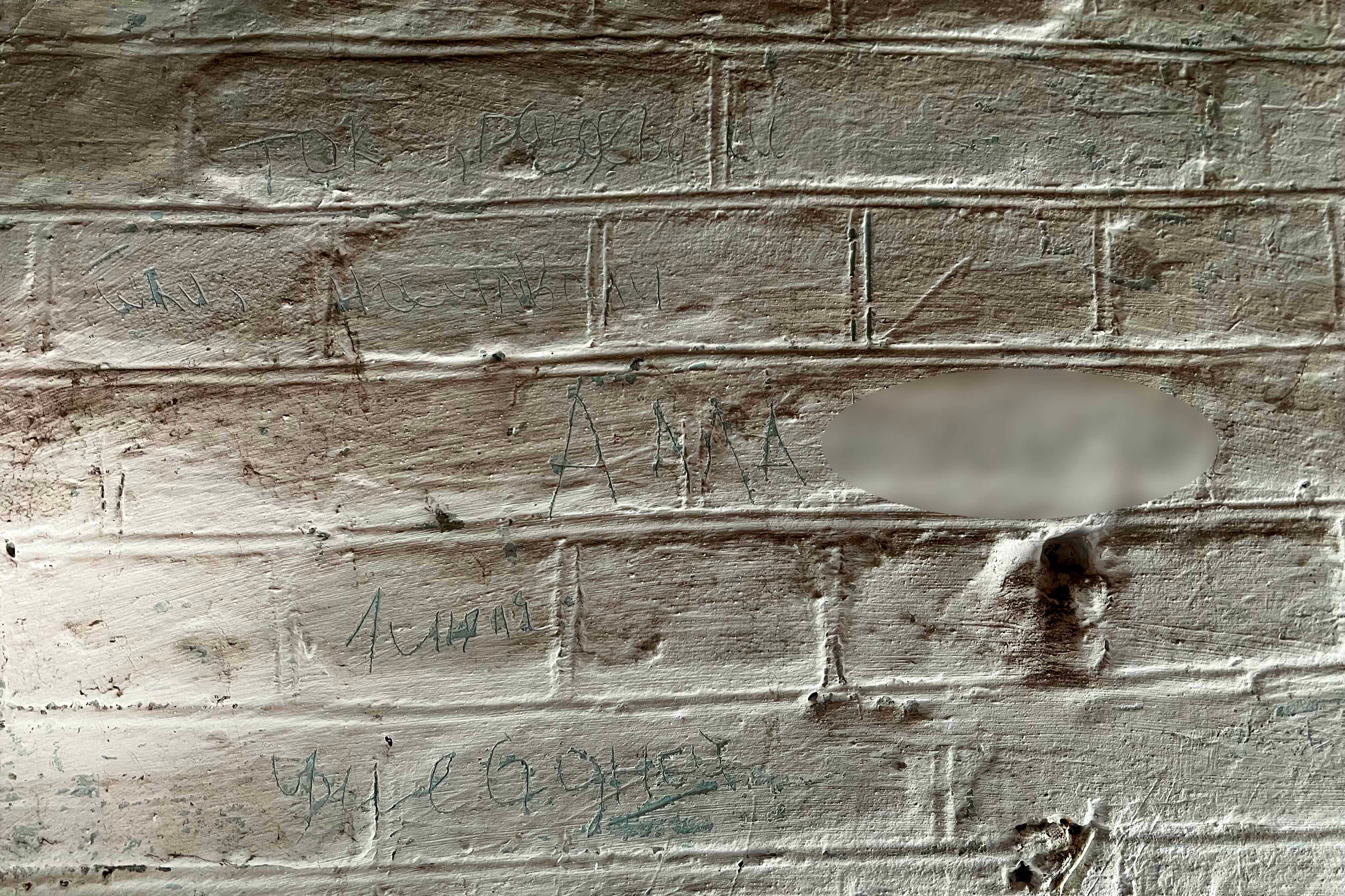 A woman who was held in a small room in a building in Izium’s City Railway Polyclinic compound in July for ten days, “Alla,” carved her full name into the wall, as well as the words and phrases “electricity, undressed or raped,” “barely alive,” “murdered,” “very painful,” and “help,” October 7, 2022. 