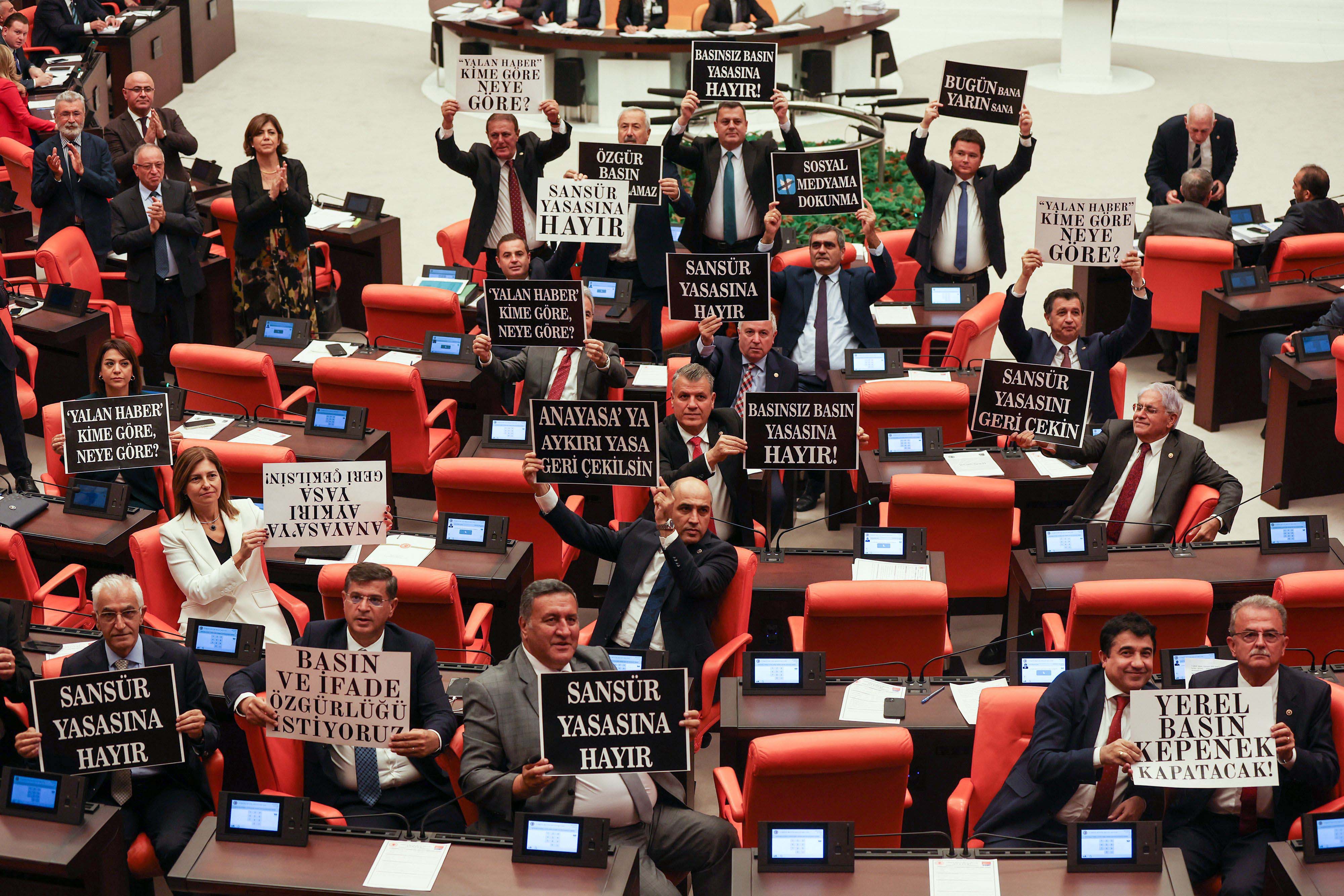 Opposition Republican People's Party deputies hold signs in protest of a government-backed bill that criminalizes "disinformation," at the Grand National Assembly of Turkey in Ankara, October 4, 2022.