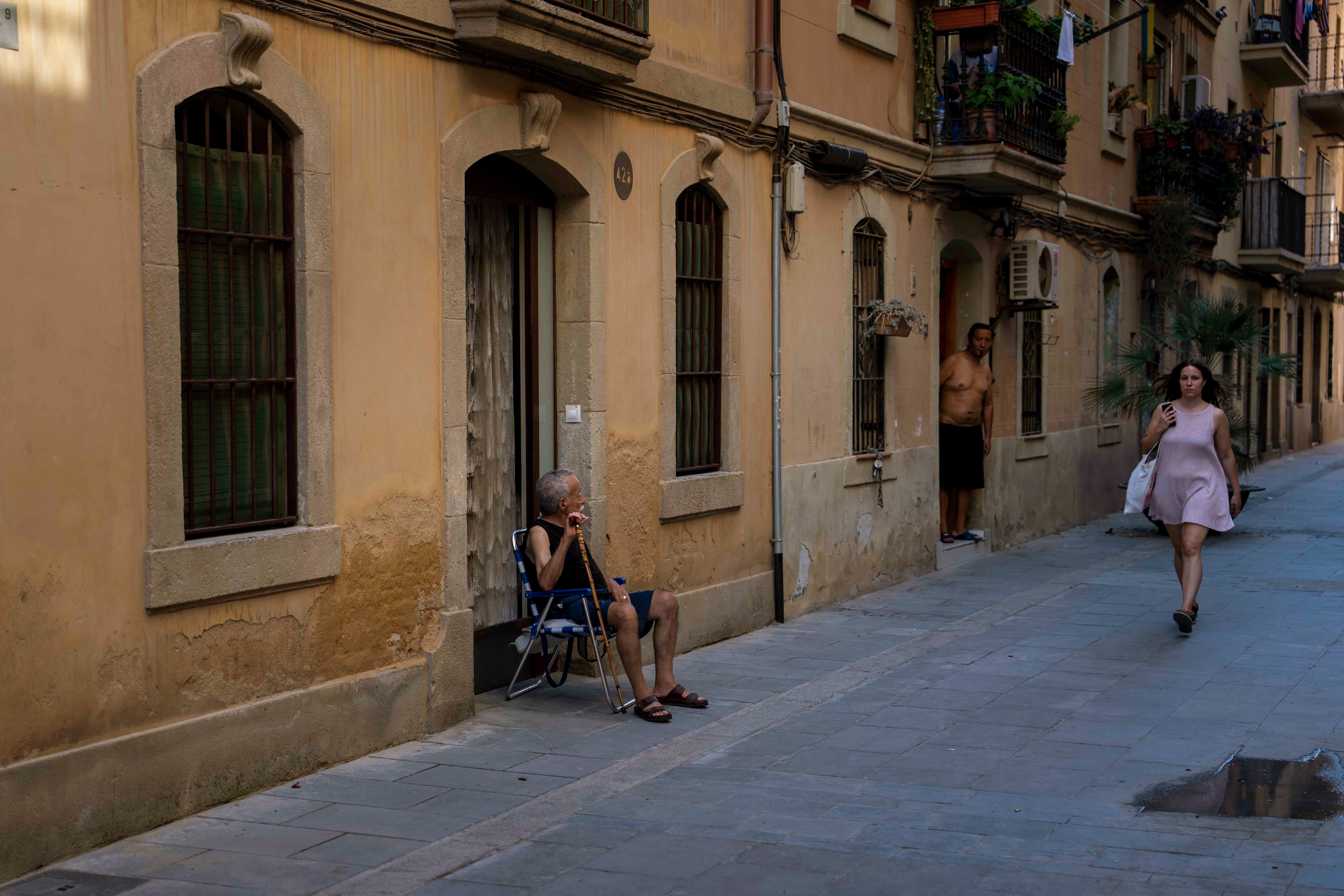 An older man sits outside his house
