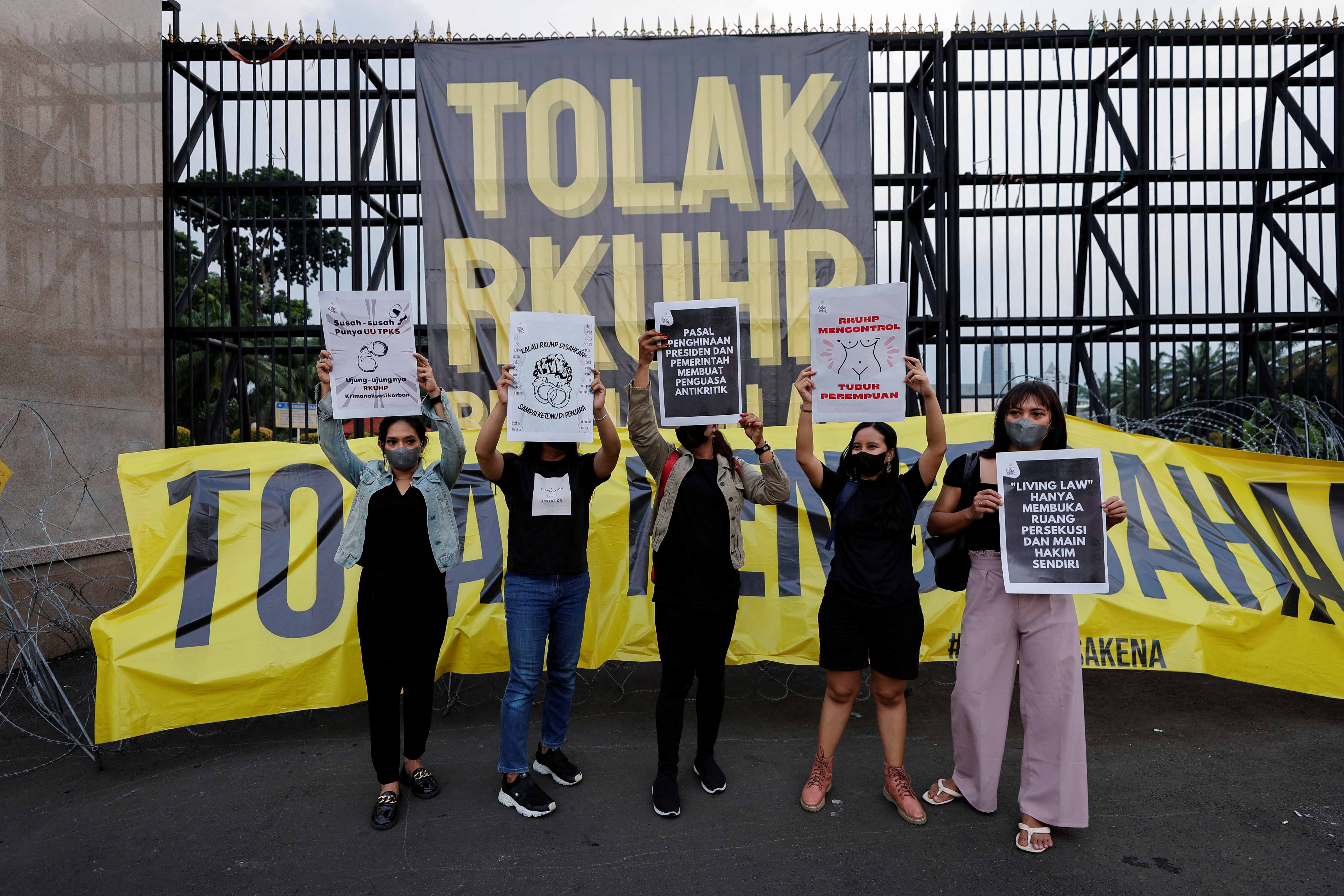 Protesters hold up signs outside parliament in Jakarta