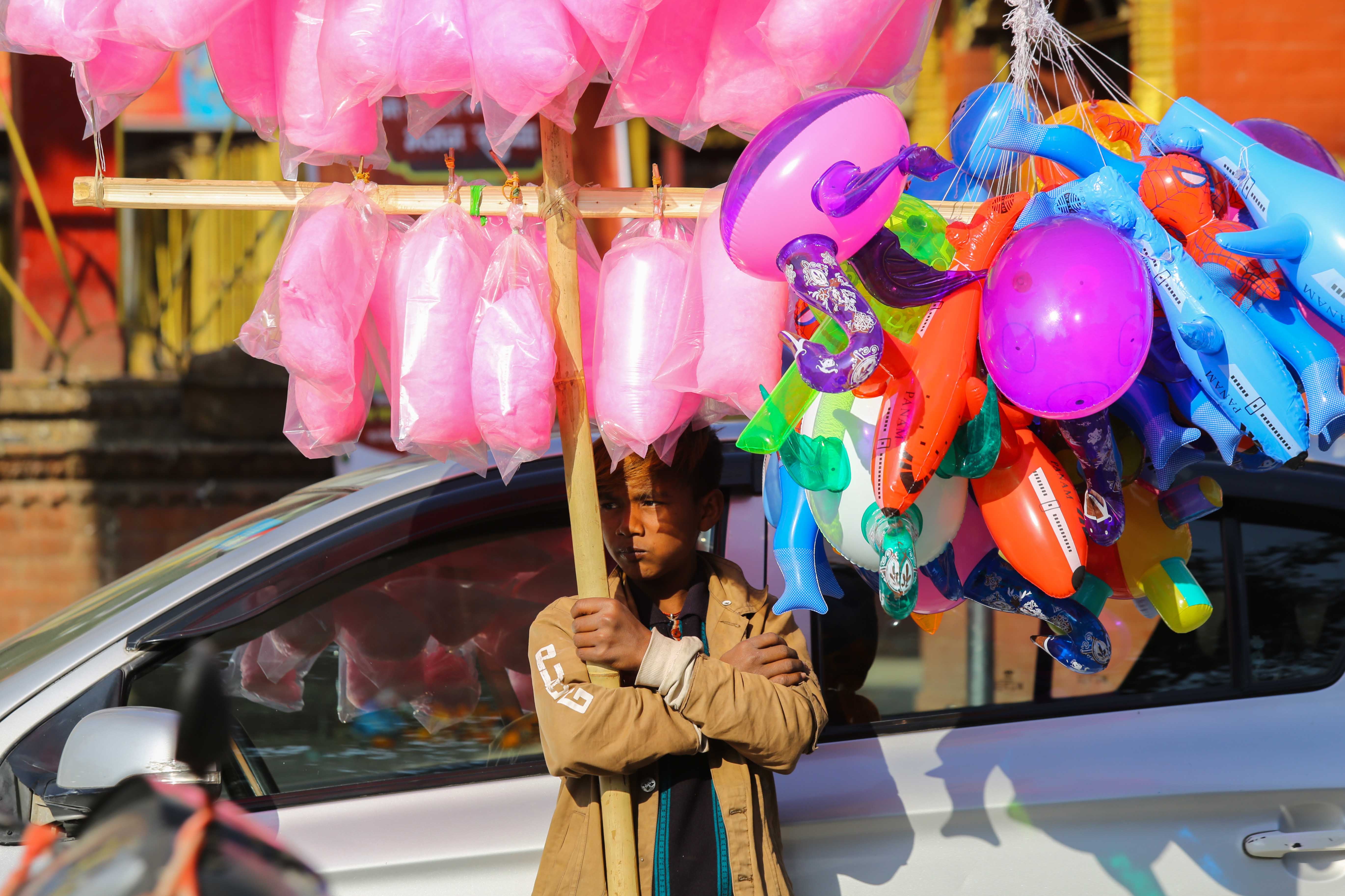 A child awaits customers to sell cotton candy and balloons in Kathmandu, Nepal.