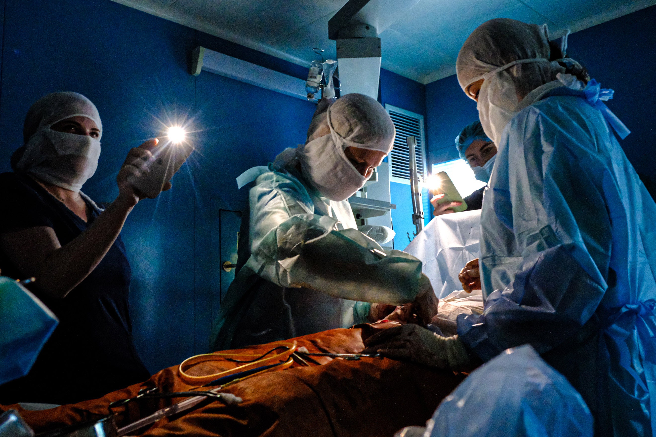 Un chirurgien effectuait une opération sous la lumière fournie par des téléphones portables dans un hôpital de Kiev, le 30 novembre 2022, lors d’une coupure d’électricité causée par l’une des nombreuses frappes russes ciblant des centrales électriques et autres infrastructures ukrainiennes.