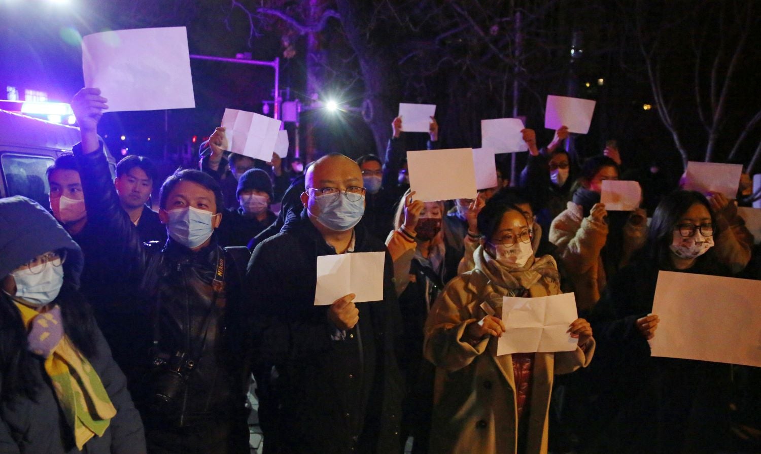 Protesters hold up blank sheets of white paper