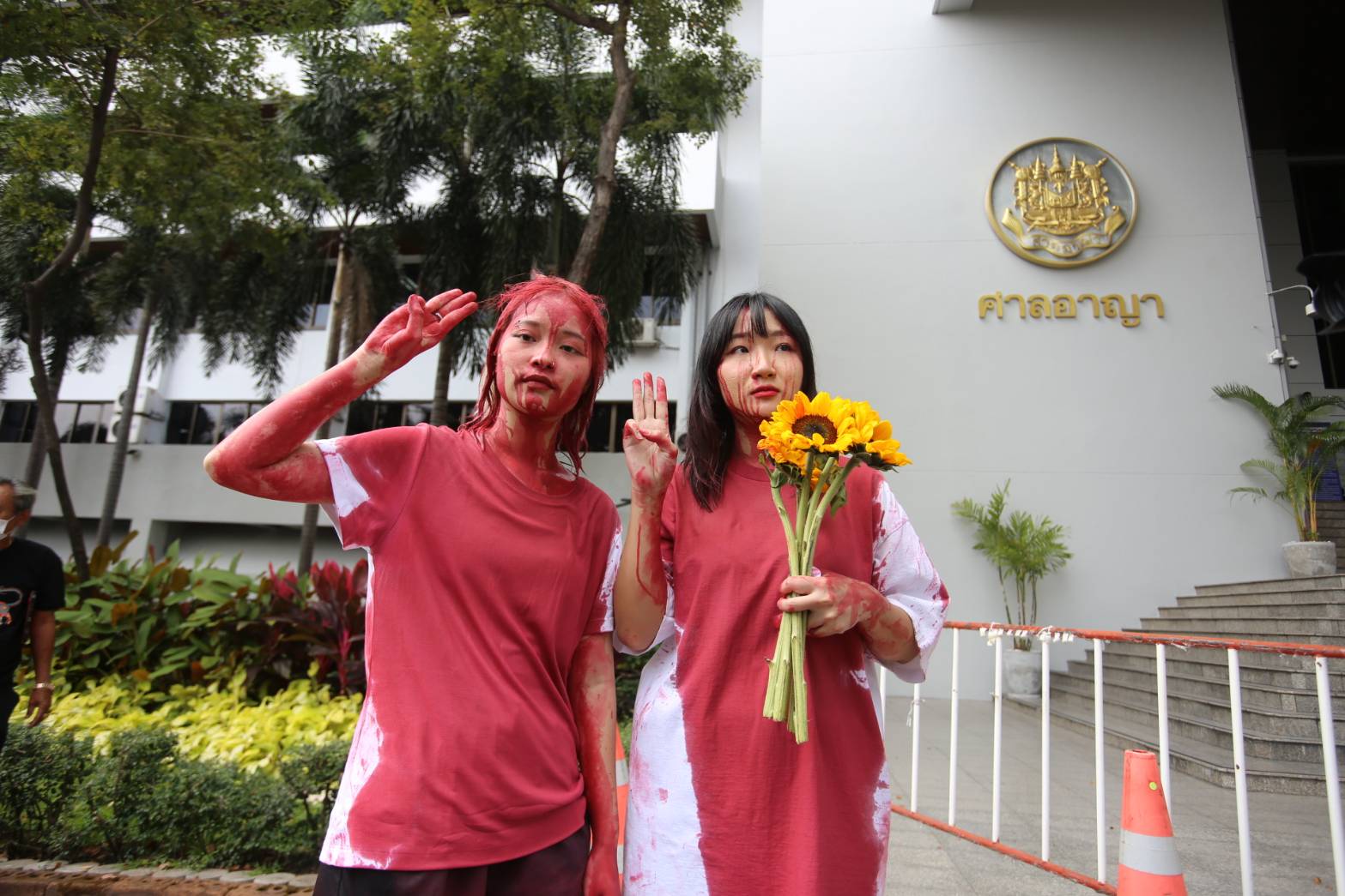 Orawan Phuphong and Tantawan Tuatulanon protest in front of the Bangkok Criminal Court by pouring red paint on themselves.