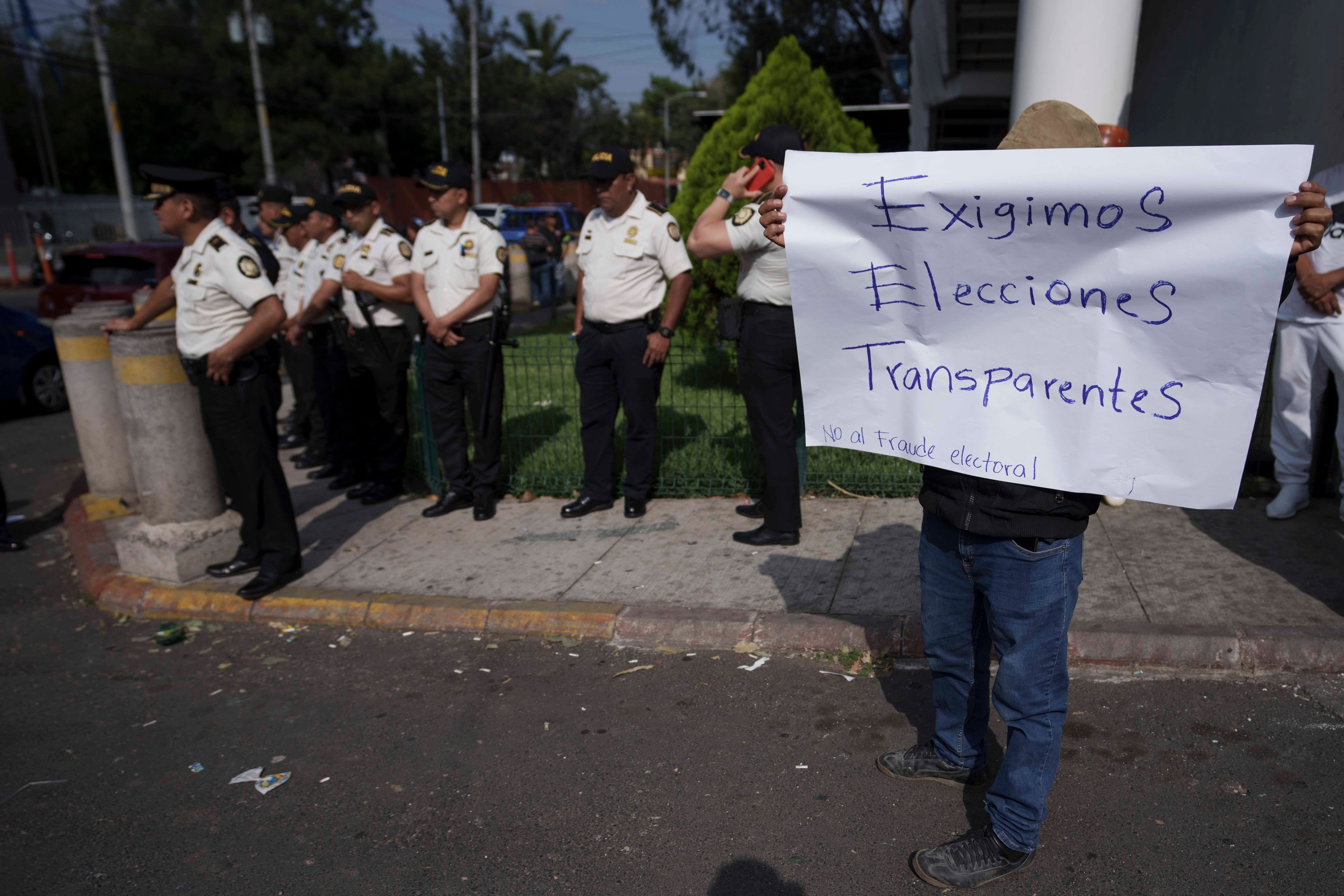 Supporters of the Liberation of the People (MLP) political party protest that the Supreme Electoral Tribunal denied the candidacy of their vice president hopeful Jordan Rodas in Guatemala City, Thursday, Feb. 16, 2023. The sign reads in Spanish "We demand transparent elections." The Electoral Tribunal has barred two candidates from running for president in the elections set for June 2023.