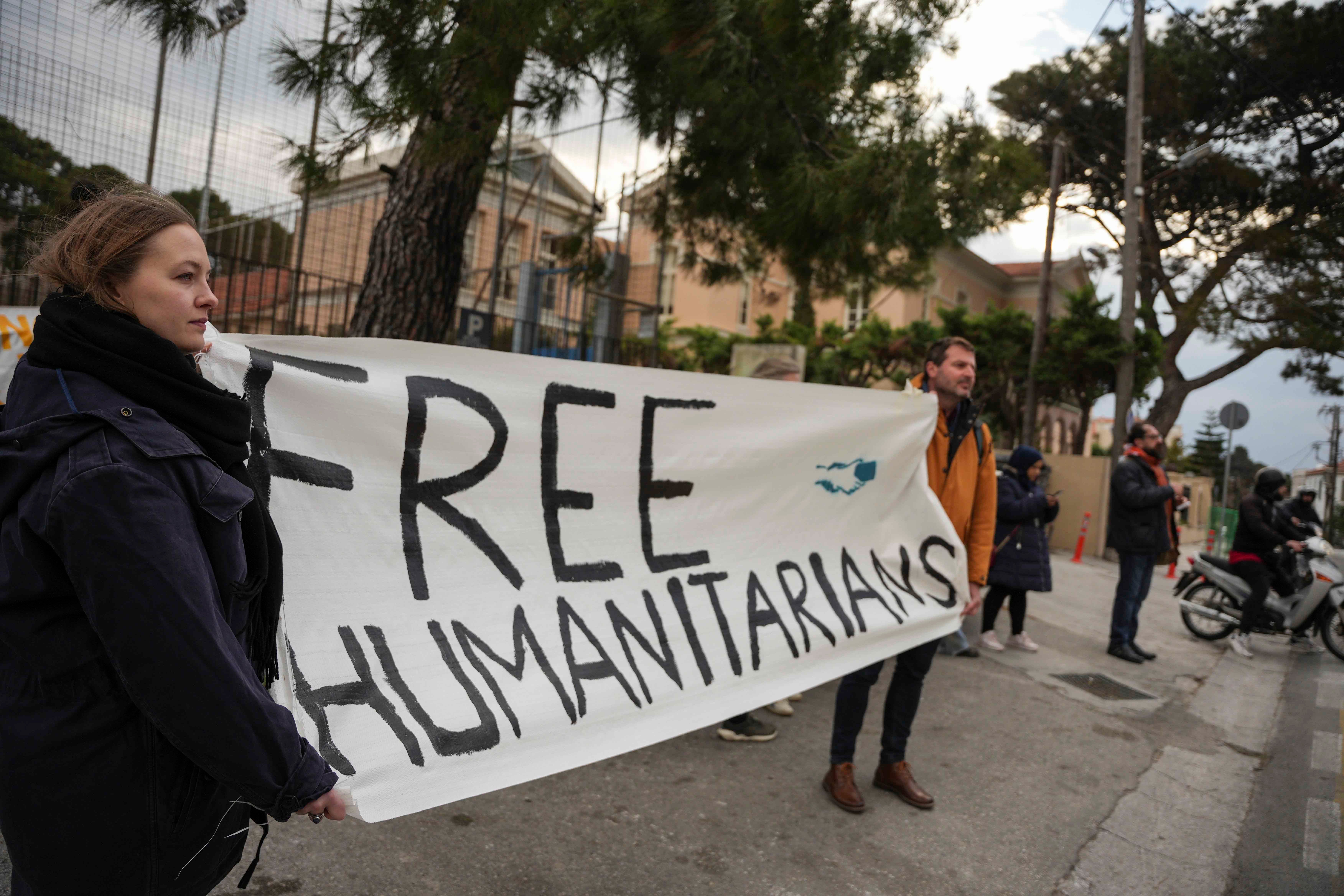 People hold a banner that reads "Free Humanitarians"
