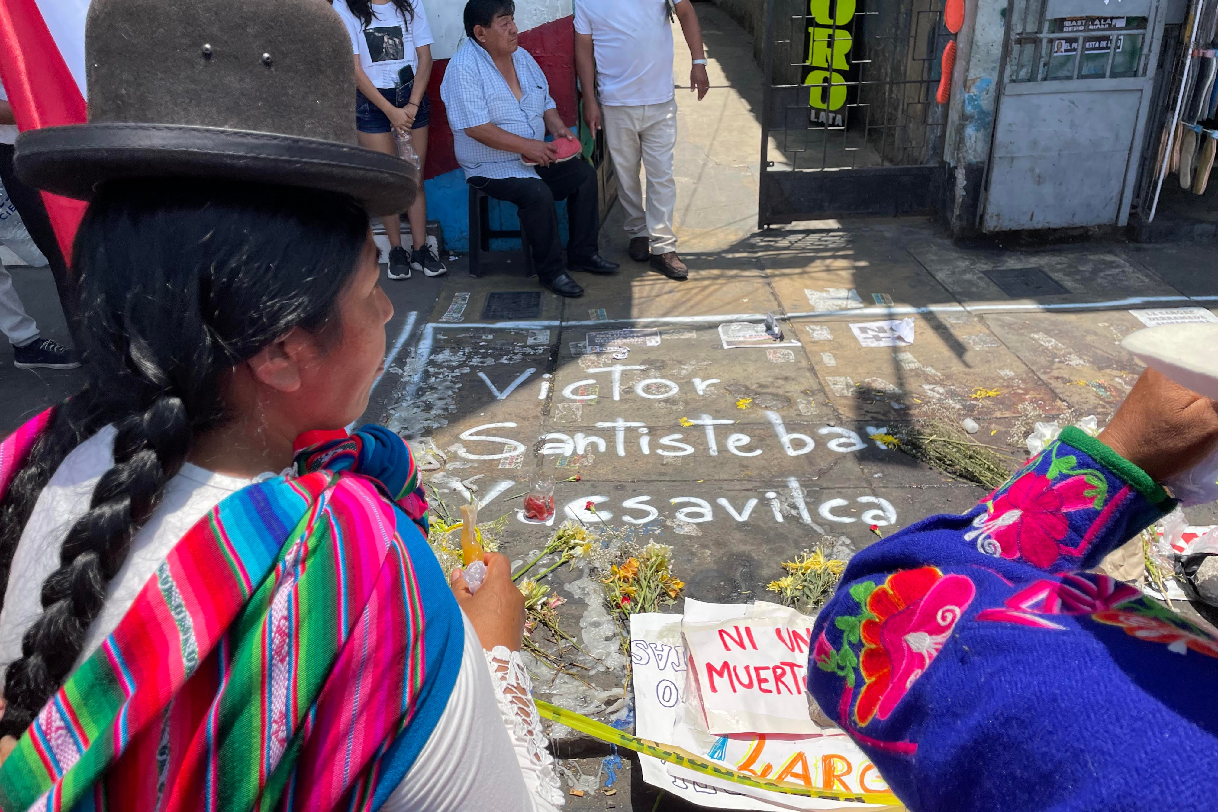 An Indigenous woman looks at a memorial to Víctor Santisteban Yacsavilca
