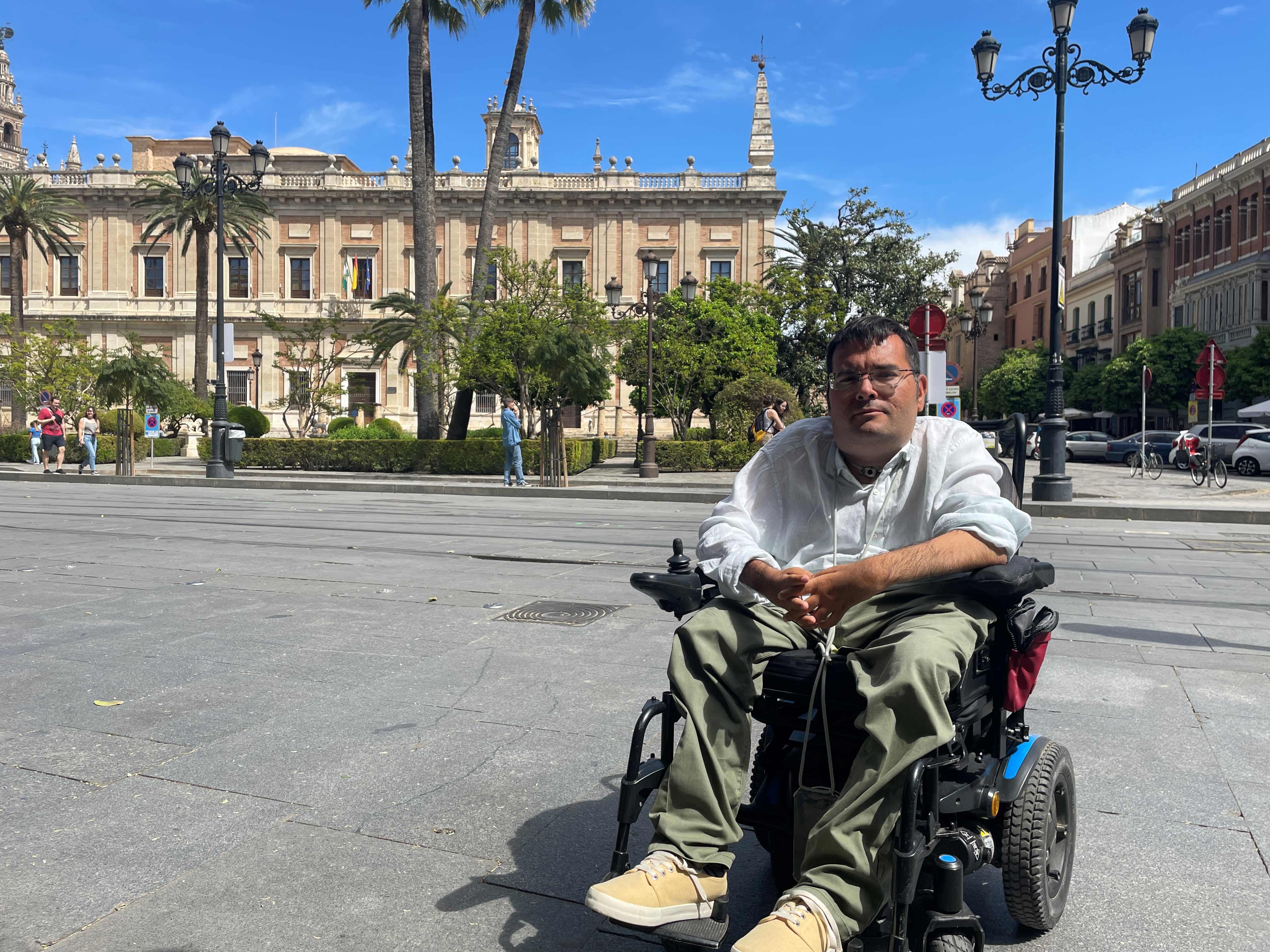 Carlos Reina Rosales, de 35 años, sentado en su silla de ruedas eléctrica, frente a un museo en el centro de Sevilla (Andalucía, España). 