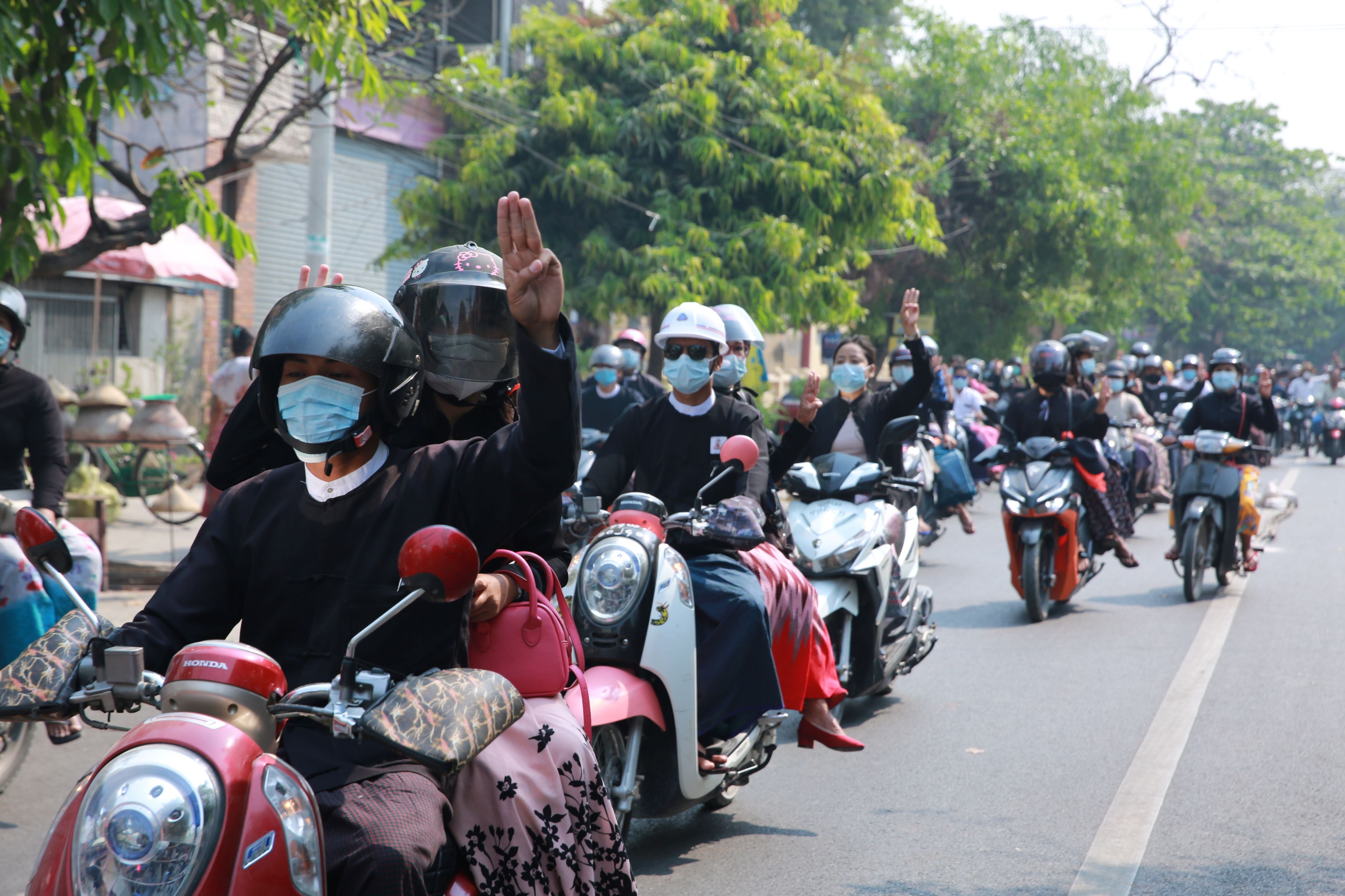 Des avocats roulant à moto à Mandalay, au Myanmar, le 15 février 2021, faisaient le salut a trois doigts pour montrer leur opposition au coup d'État militaire mené deux semaines auparavant. 
