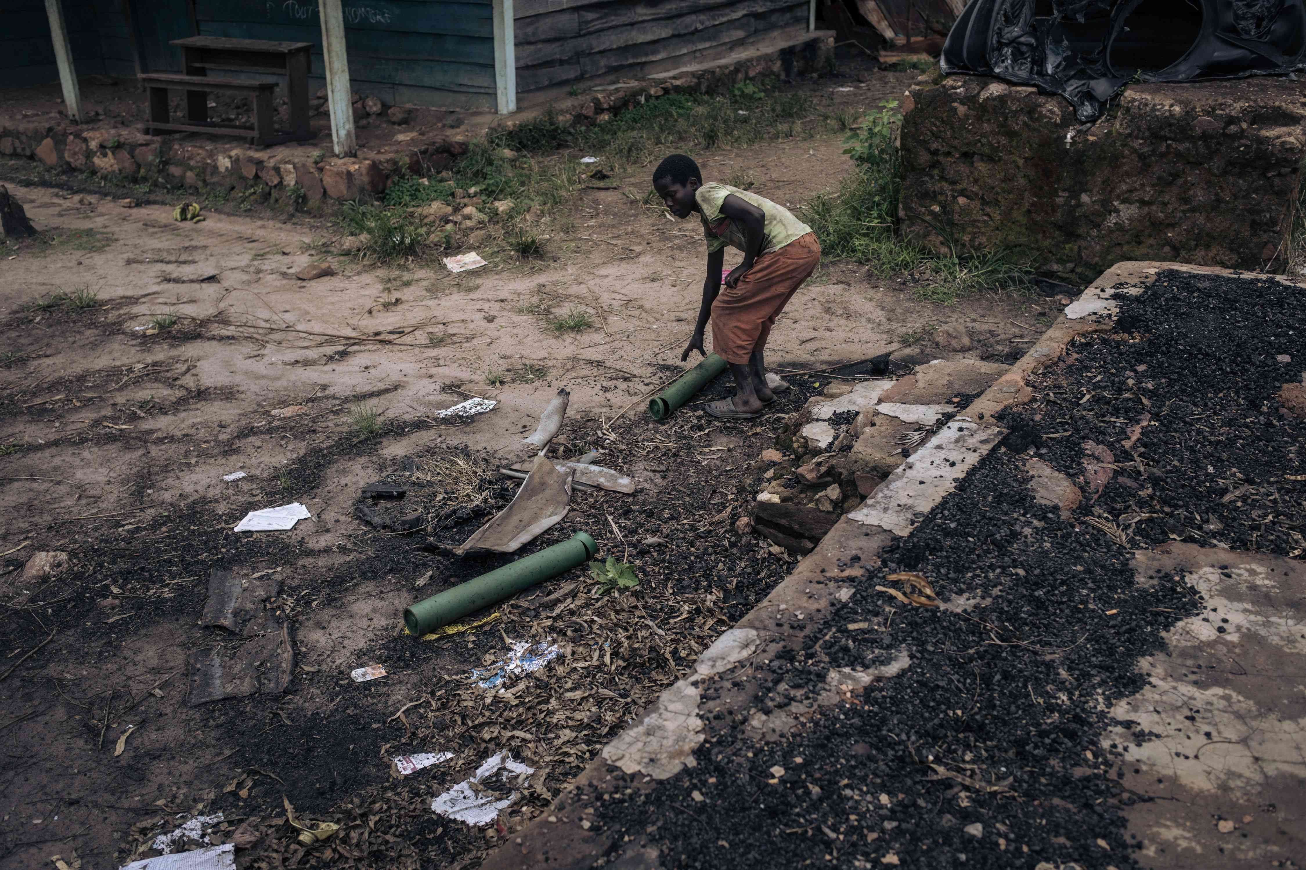Un garçon ramasse des douilles de mortier dans les ruines d’un établissement scolaire utilisé comme base militaire et prétendument détruit par les combattants du M23 à Kishishe, au Nord-Kivu, en République démocratique du Congo, le 5 avril 2023.