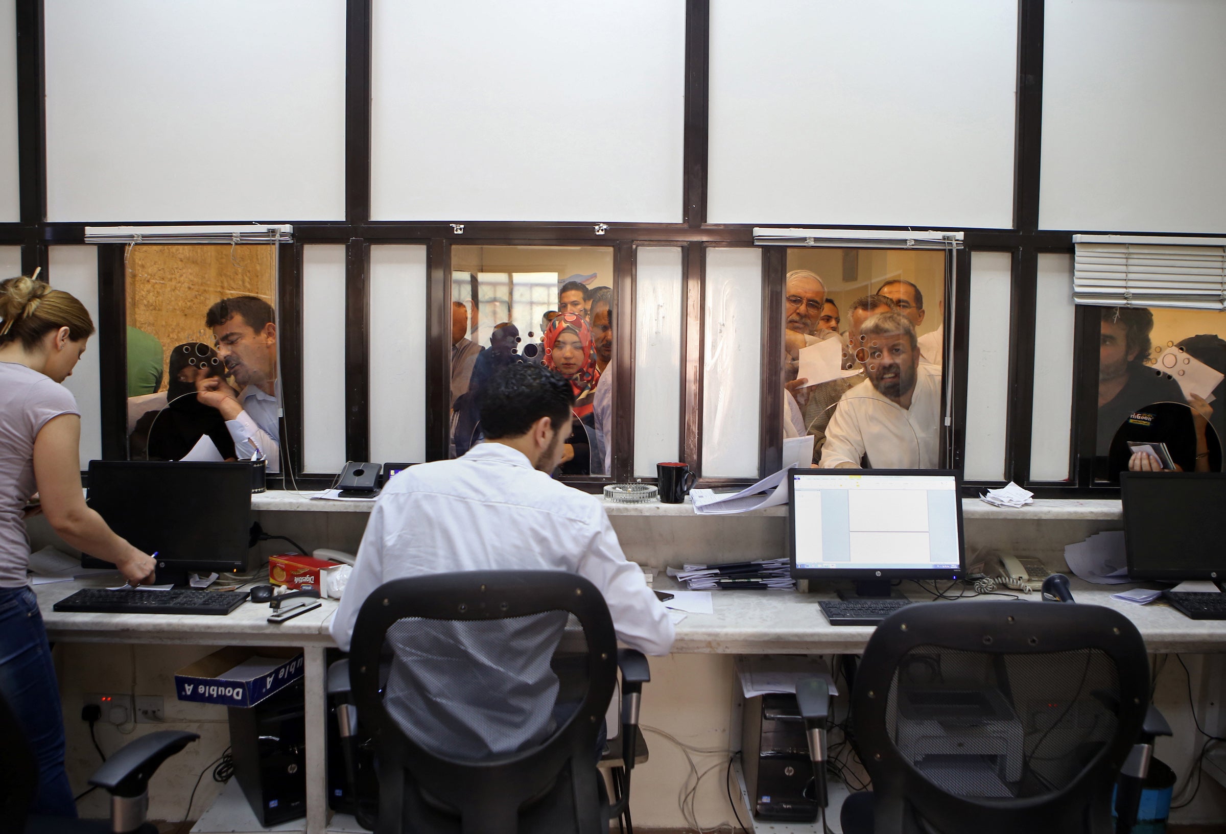 Syrians line up to apply for passports inside of the Embassy of Syria in Amman, Jordan, September 15, 2015.