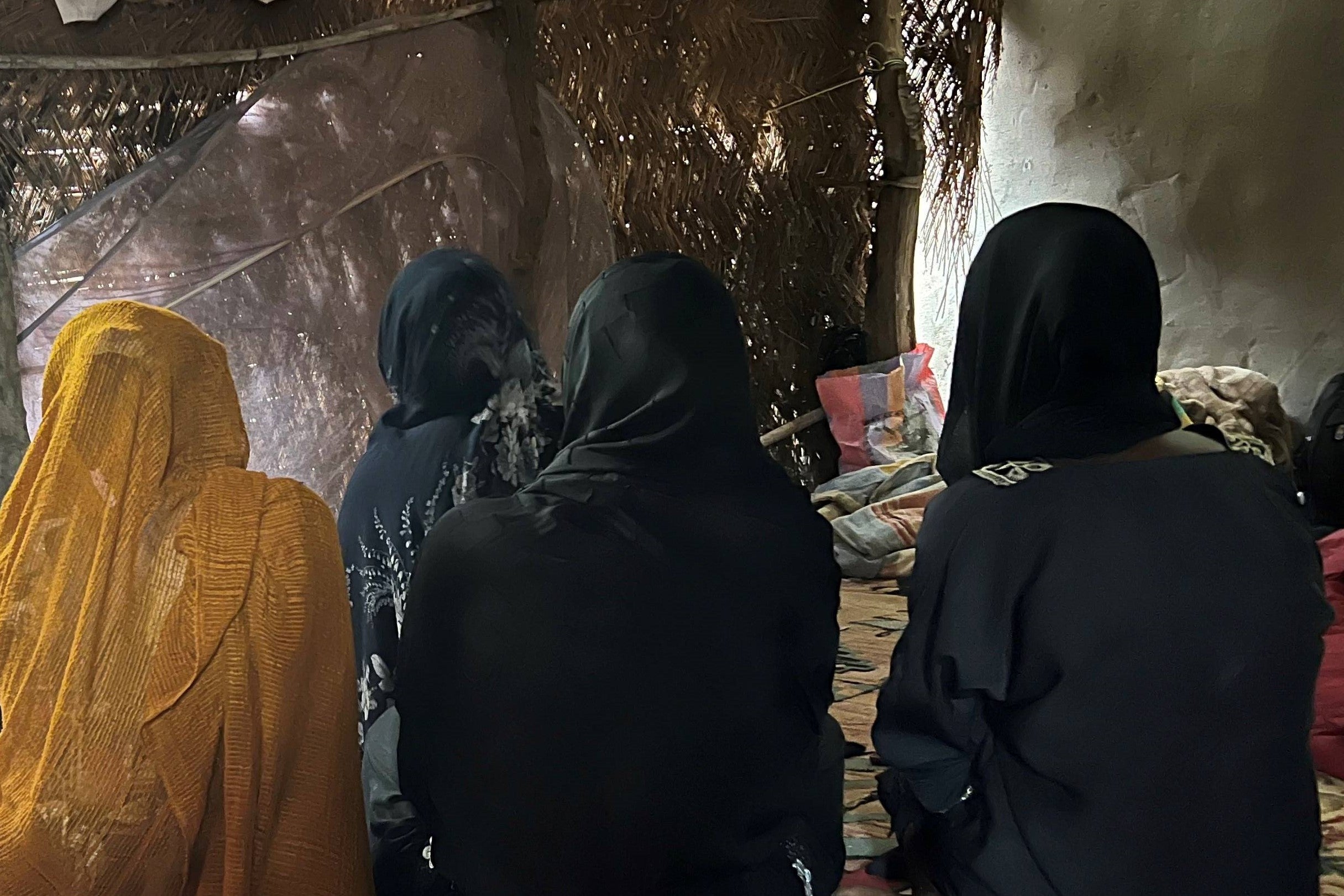 A group of women seated on the floor with their faces obscured.