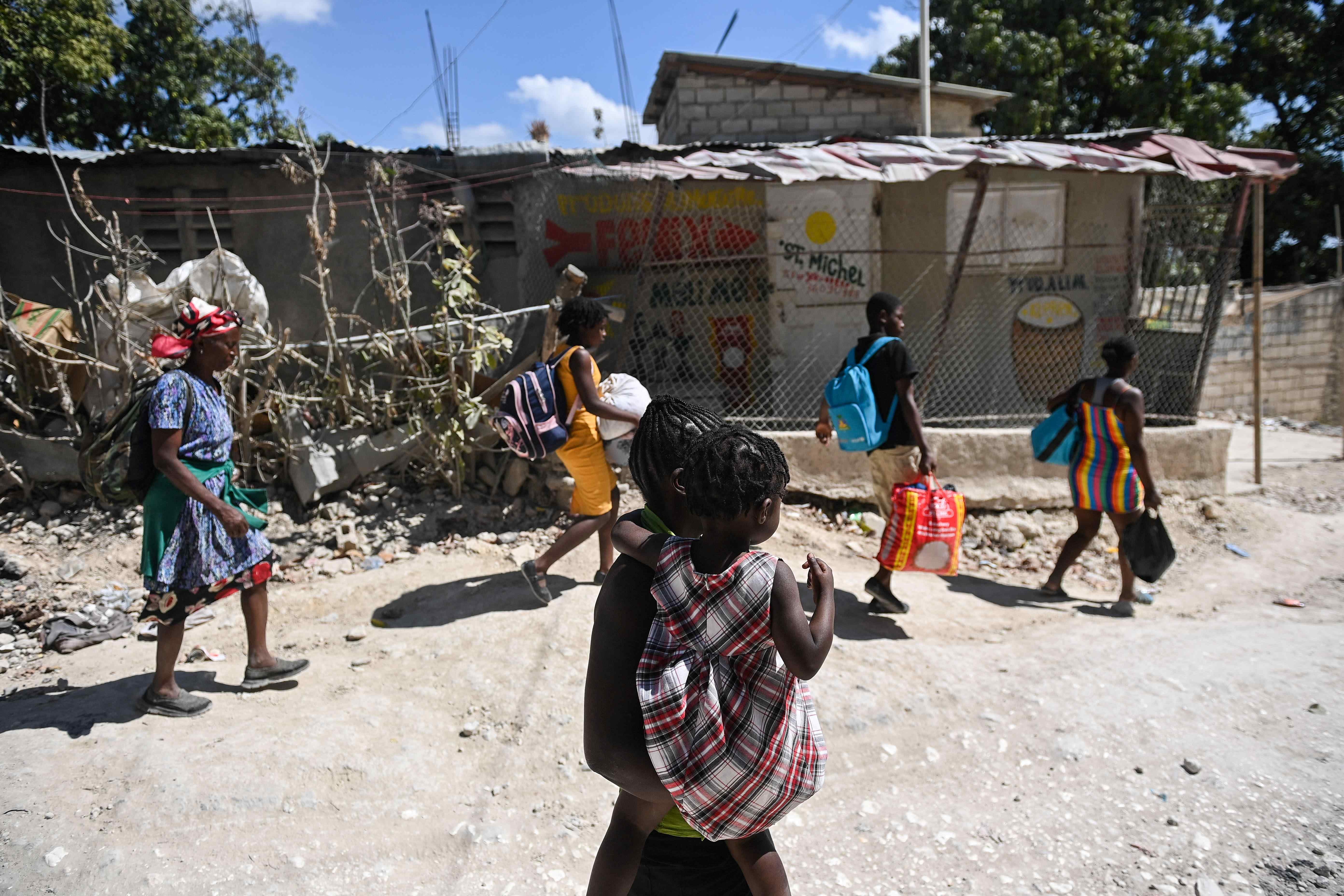 A group of people carry their belongings on a city street 