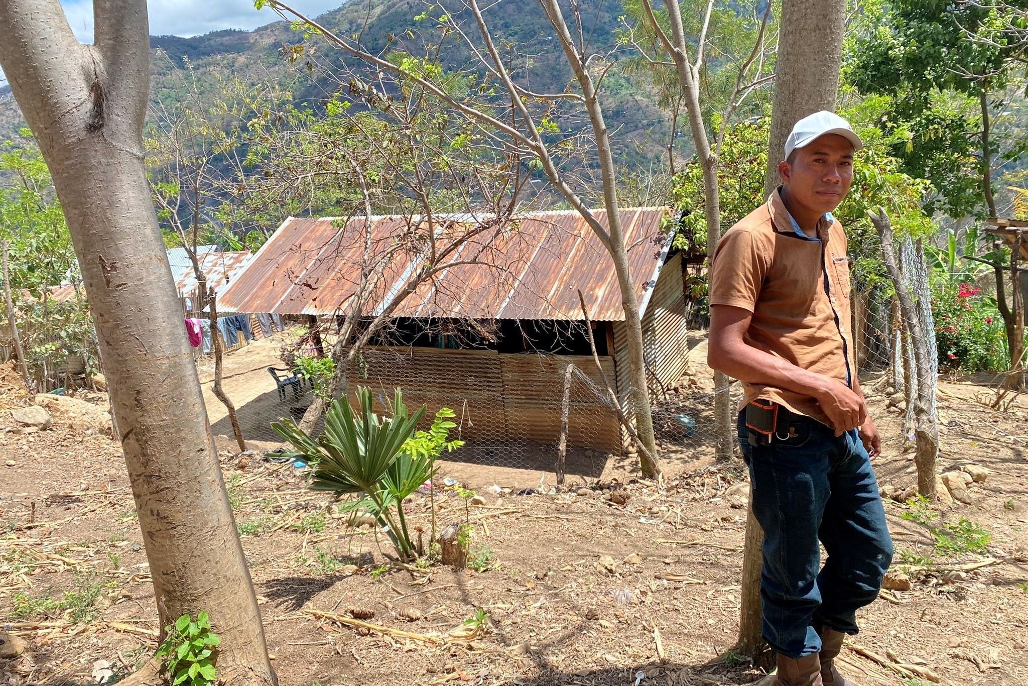 A farmer stands outside of his home in a village