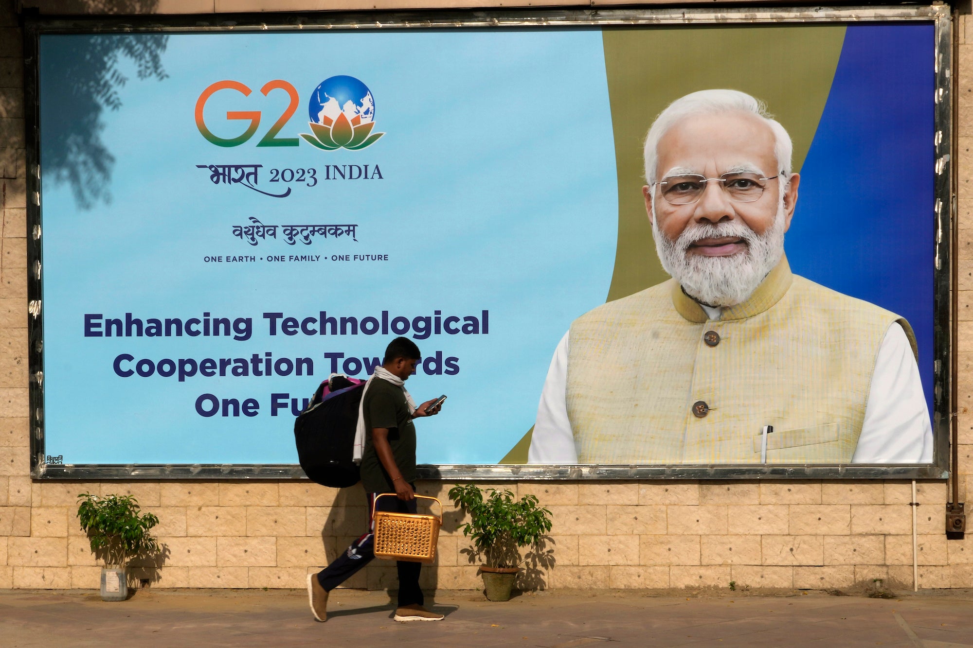 A migrant laborer walks past a billboard ahead of the summit of the Group of 20 nations in New Delhi, September 4, 2023.