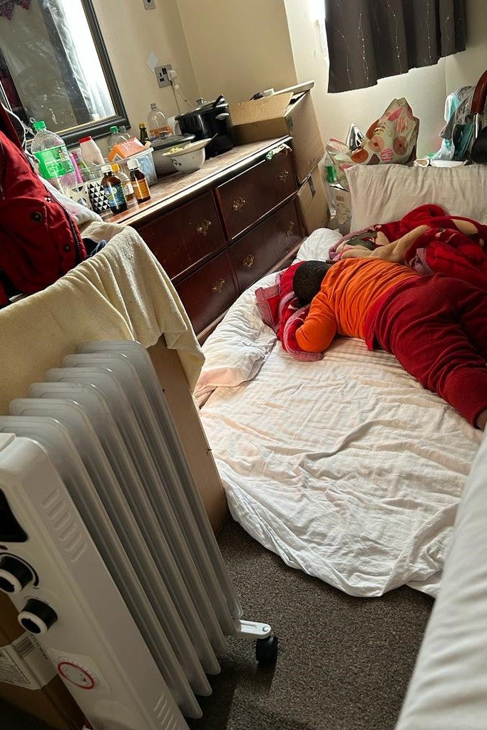A boy sleeps on a mattress on the floor