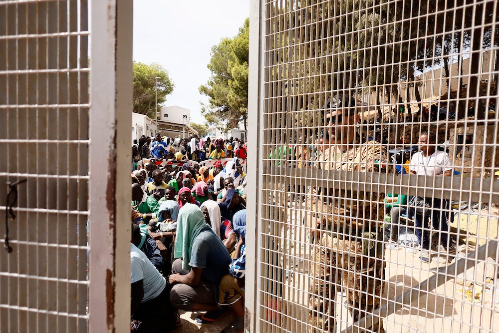 People sit on the ground of the overcrowded migrant reception center on Lampedusa, an Italian island in the Mediterranean Sea, on September 16, 2023.