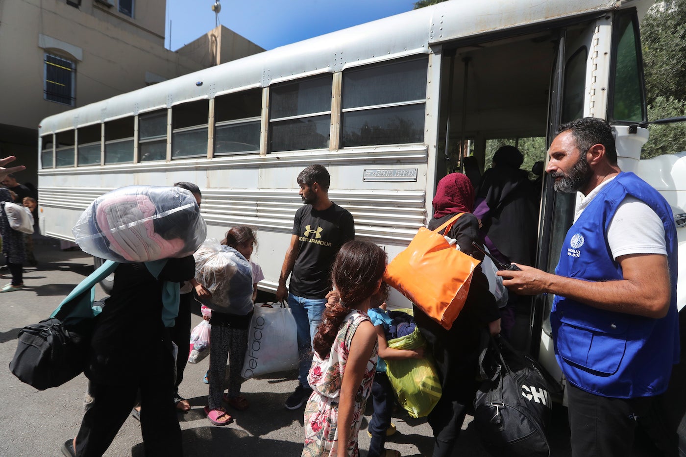 Palestinian residents who fled their houses in the Palestinian refugee camp of Ein el-Hilweh, carry their belongings as they board a bus to be moved from Sidon municipality to an UNRWA (United Nations Relief and Works Agency for Palestine Refugees) school, in the southern port city of Sidon, Lebanon, September 12, 2023. 