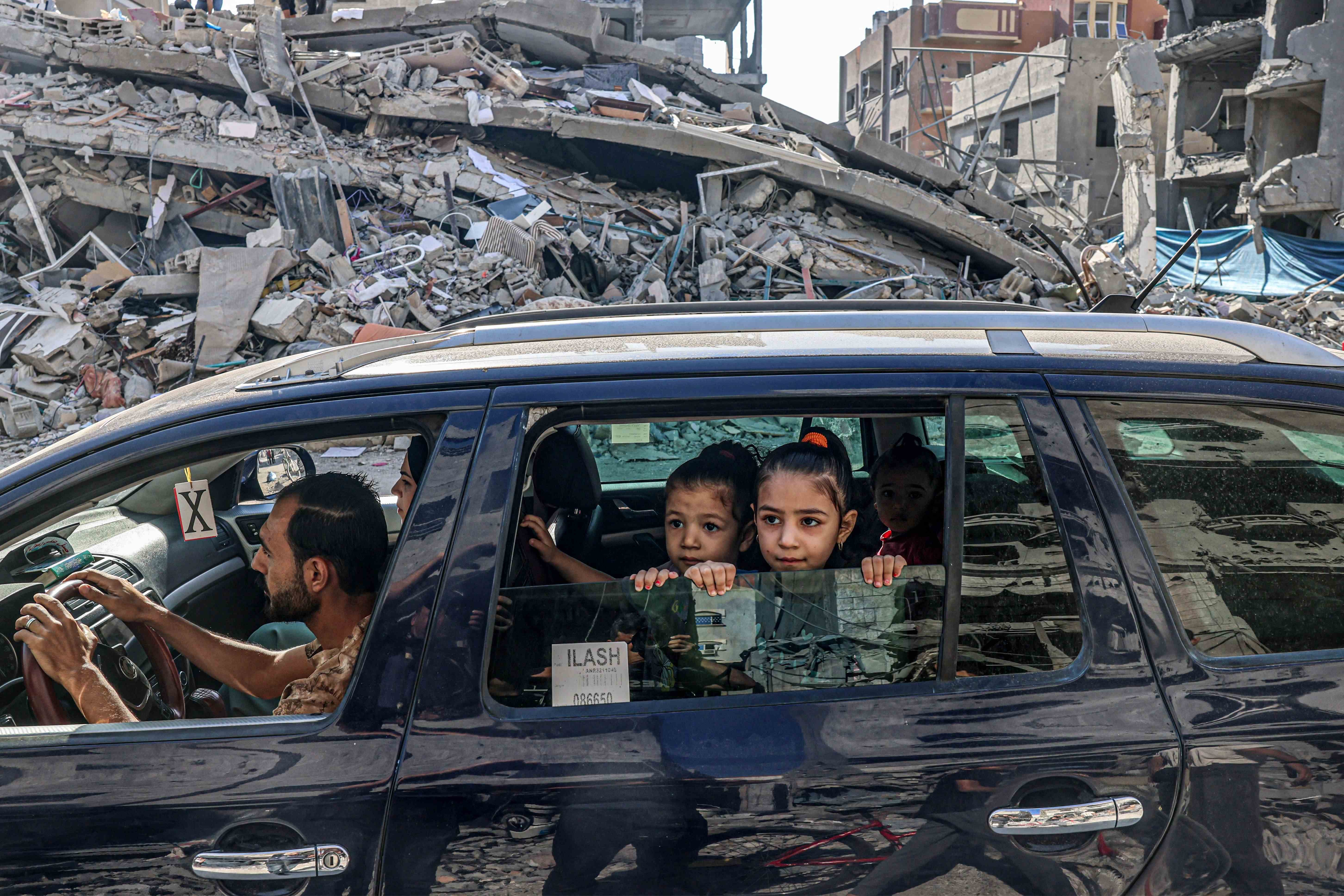 פלסטינים נוסעים בין חורבות מבנים שנהרסו בתקיפה אווירית ברפיח שבדרום רצועת עזה, 12 באוקטובר 2023