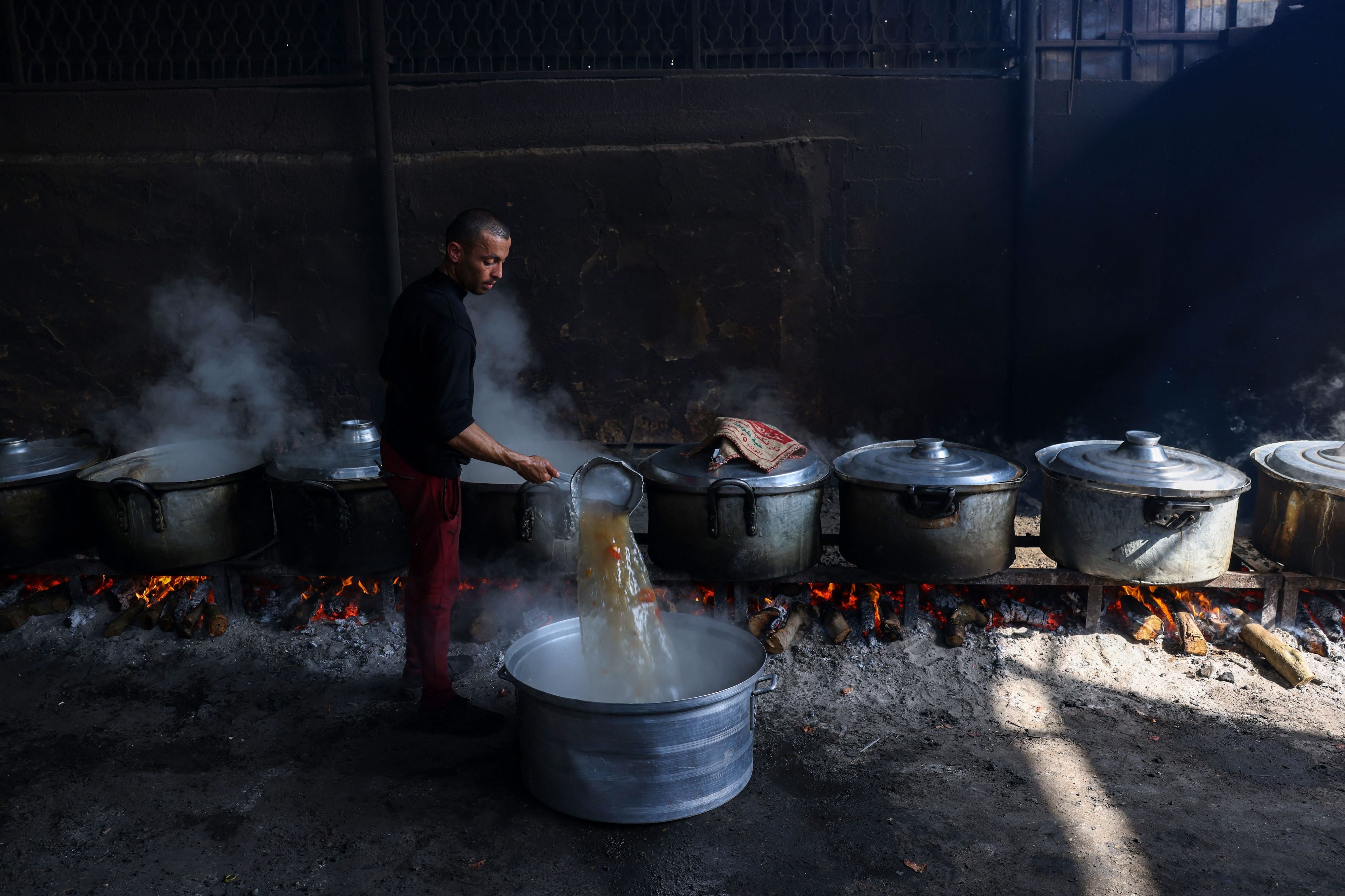 Palestinians prepare meals at a UN shelter to be distributed to displaced people in Rafah, in the southern Gaza Strip, October 23, 2023.