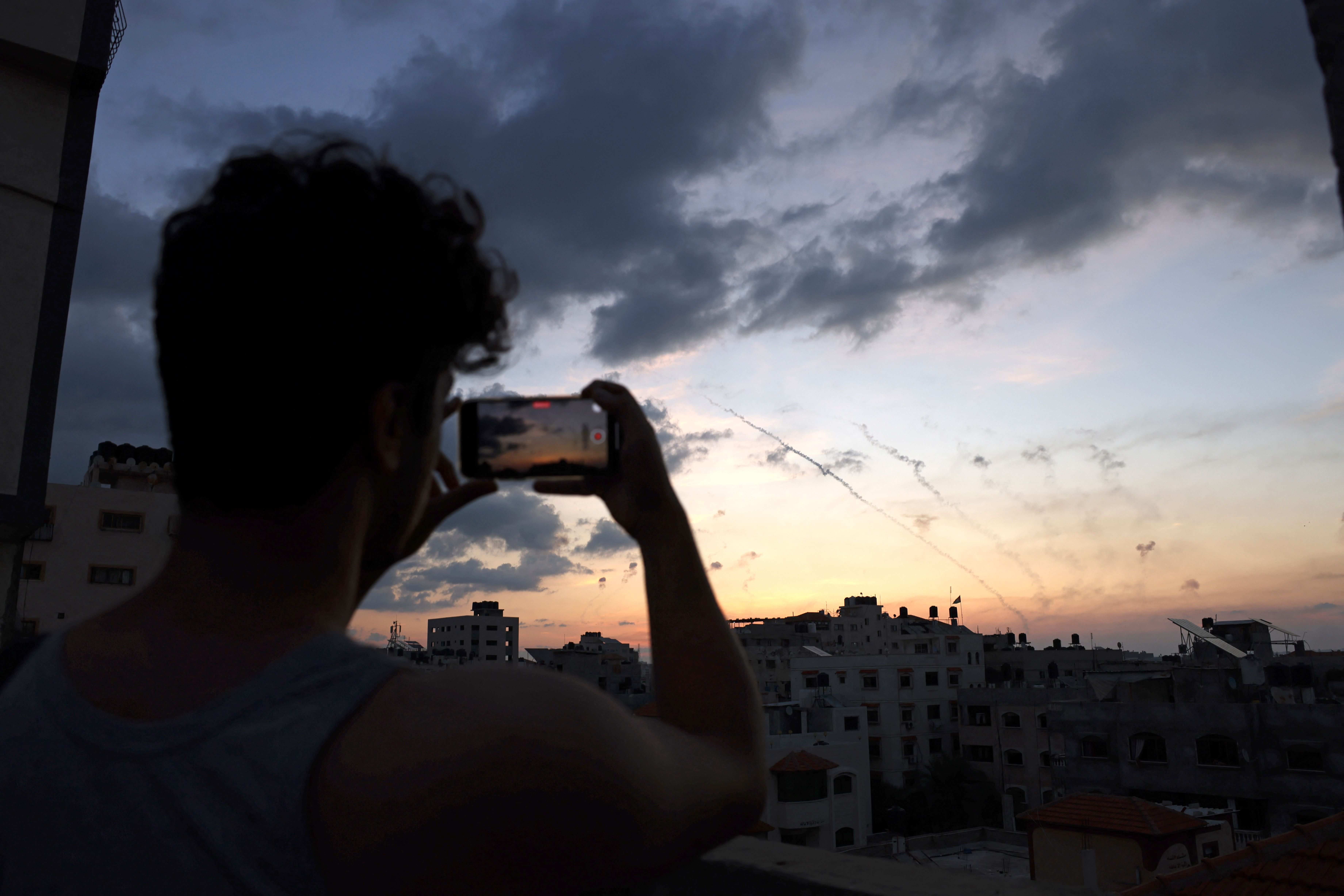 Ein Mann filmt mit seinem Handy, wie Raketen aus Gaza-Stadt in Richtung Israel fliegen, 7. Oktober 2023.